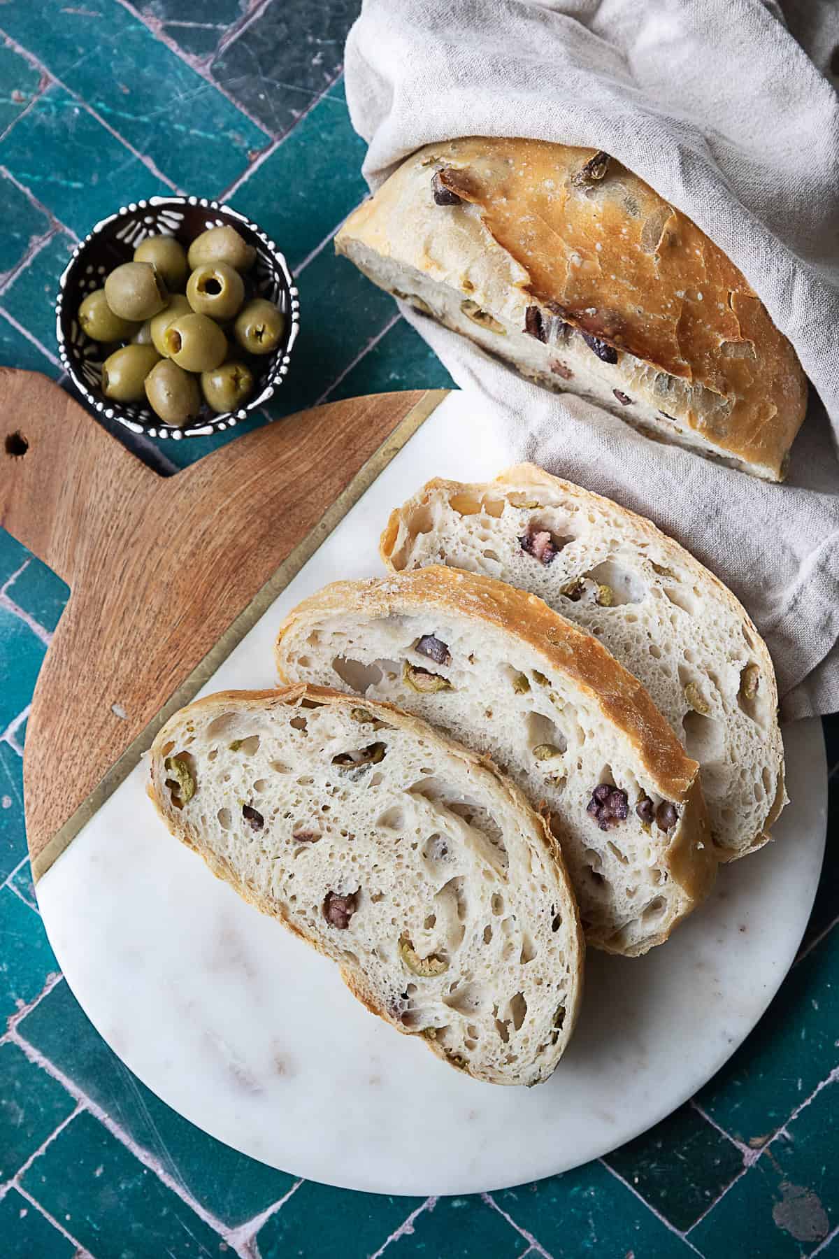No-Knead Olive Bread Freshly baked No-Knead Olive Bread with a golden, crispy crust and chunks of kalamata and green olives visible throughout