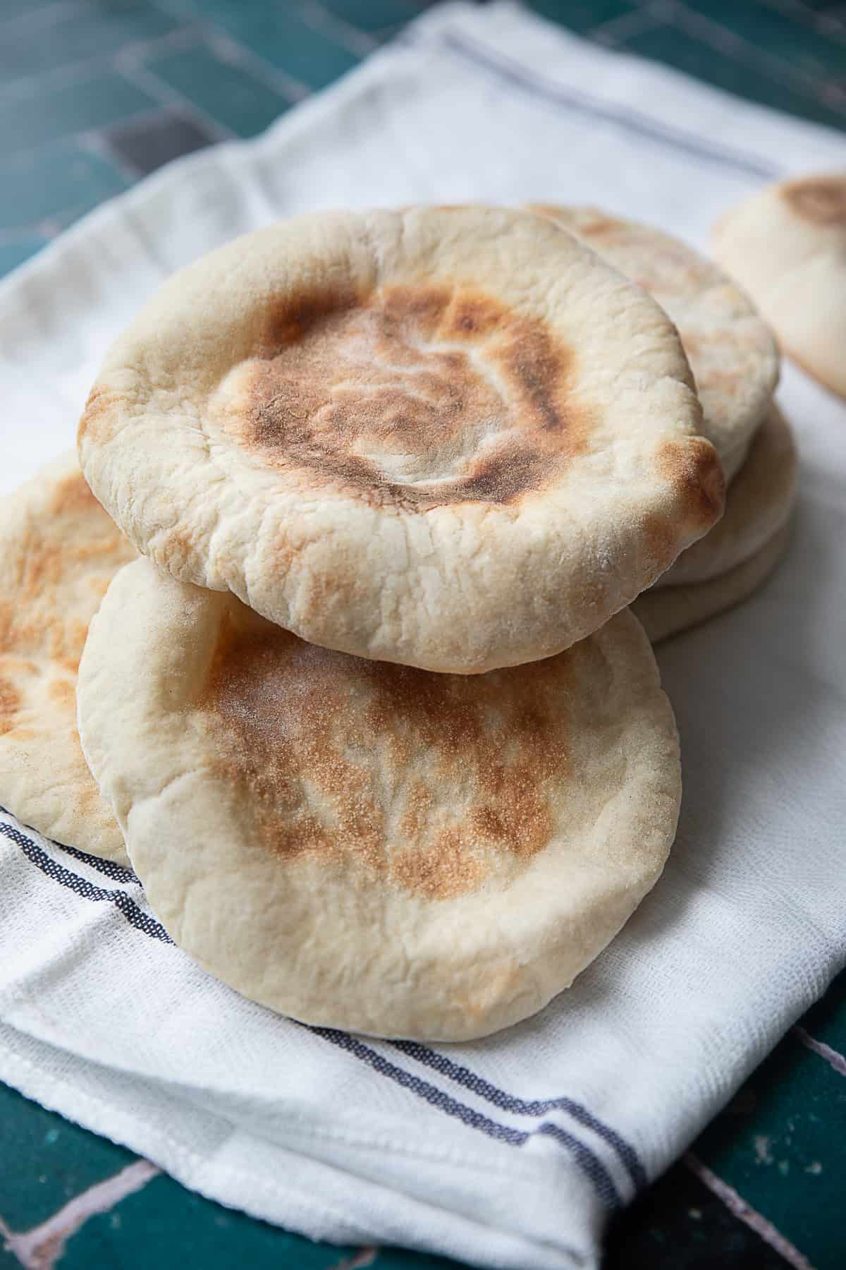 Homemade Pita Bread A few pita bread loaves on a kitchen towel.