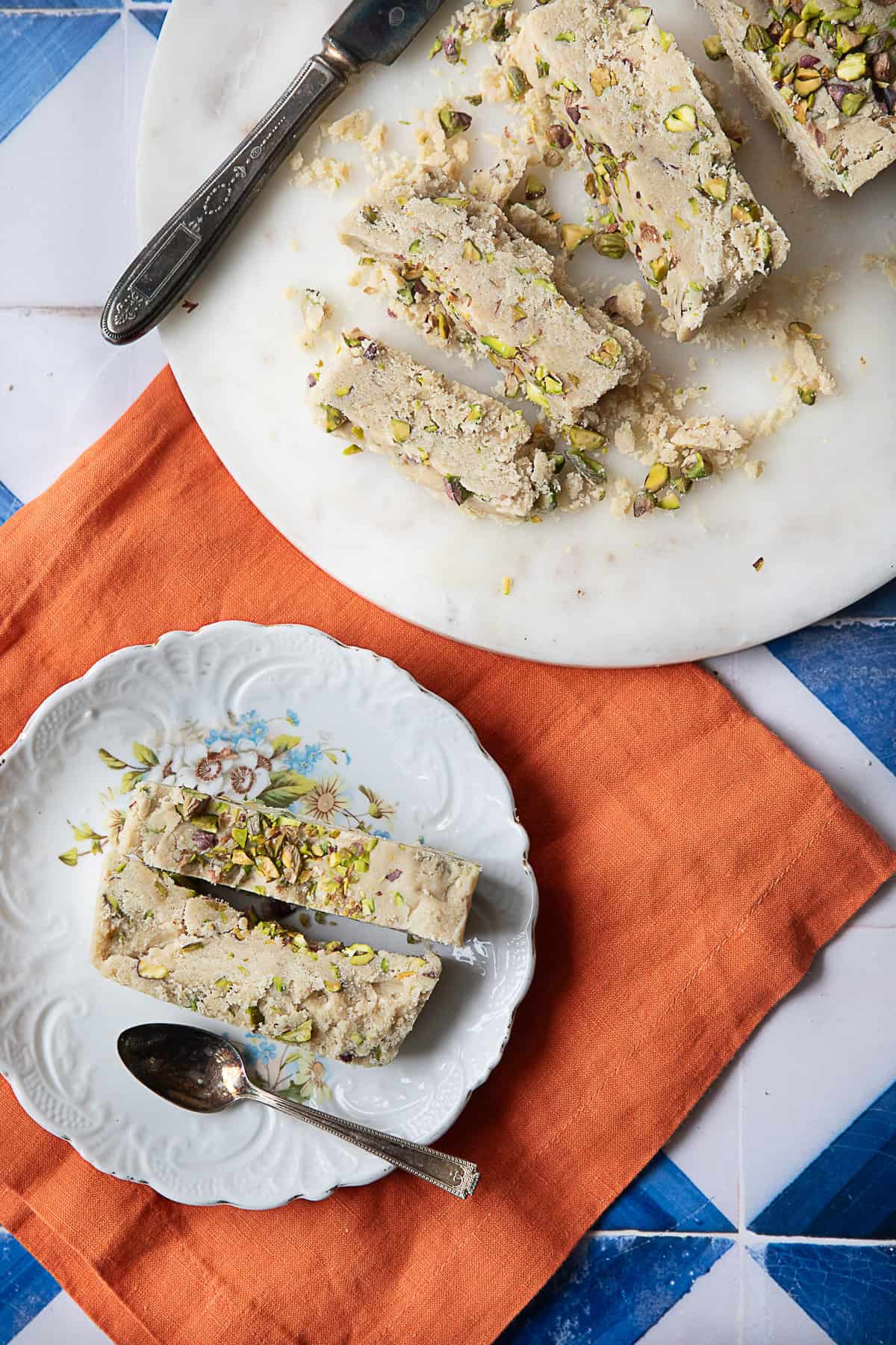 Best Tahini Halva tahini halva pieces served up in white plate with more tahini halva pieces in a larger serving plate in the background