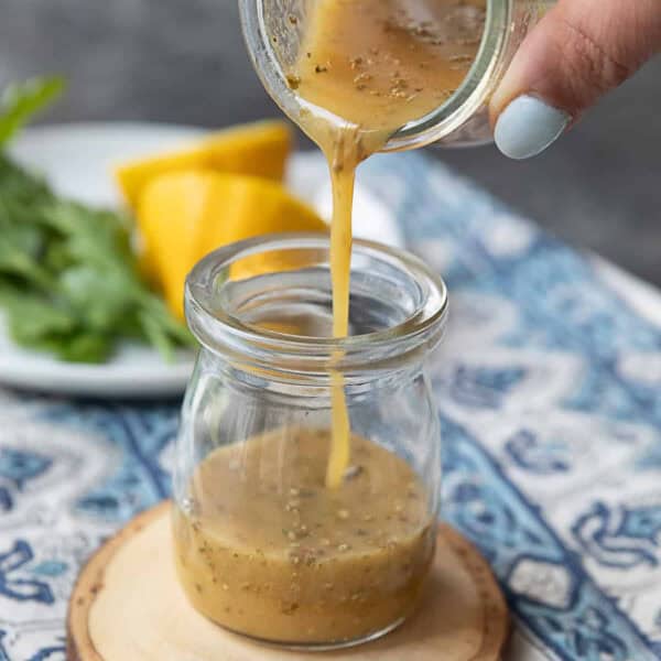 a close up view of a jar of Dijon vinaigrette with a spoon