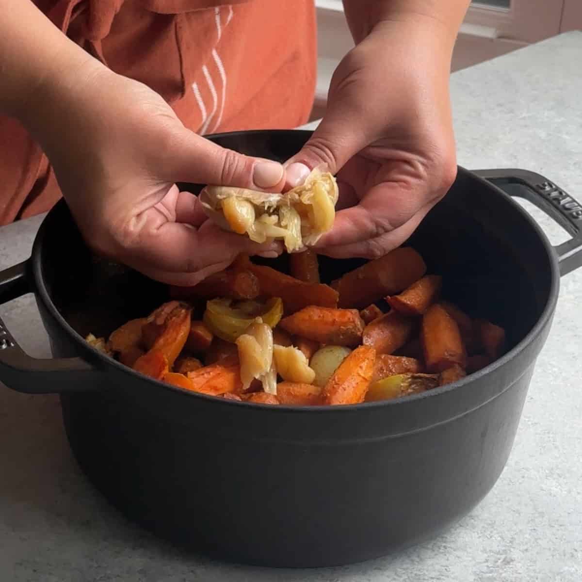 How to Make Roasted Carrot Soup squeeze roasted garlic into the pot with the roasted vegetables.