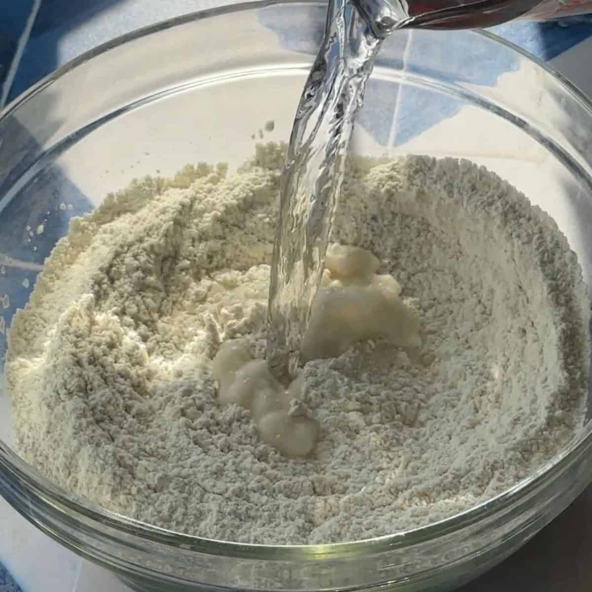 a glass bowl containing ciabatta bread ingredients drizzled with water