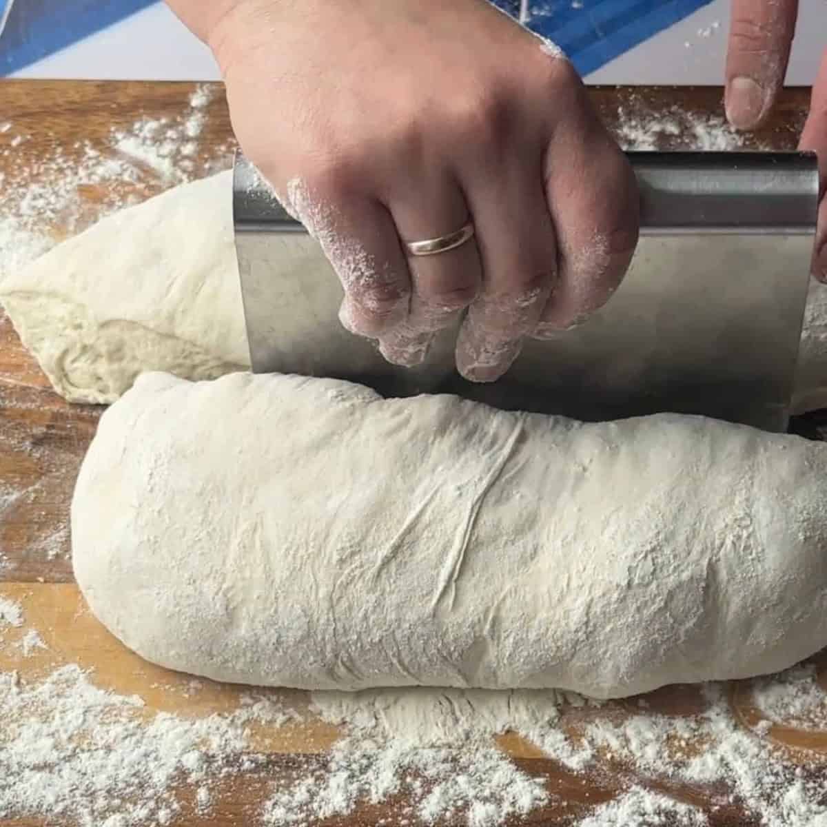 ciabatta dough placed on a floured surface cut with a scraper