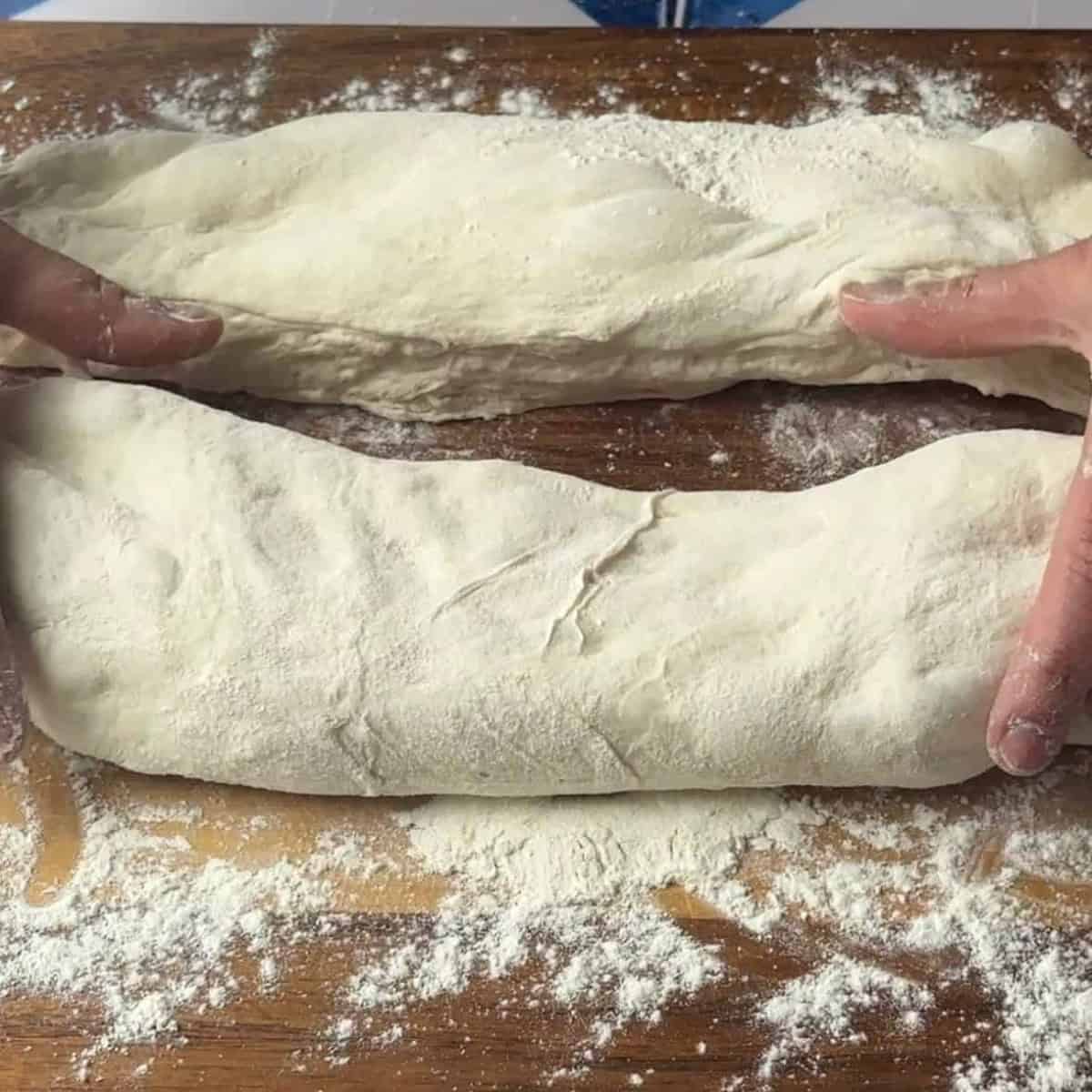 2 pieces of ciabatta dough placed on a floured surface
