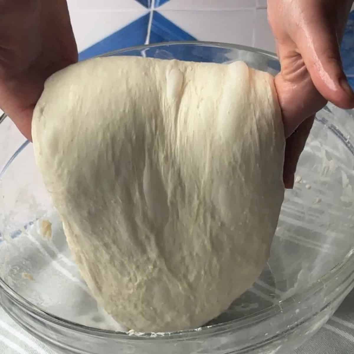 Close-up of ciabatta dough, showing a sticky, high-hydration mixture with visible air bubbles, lightly folded to develop structure using the stretch-and-fold technique.