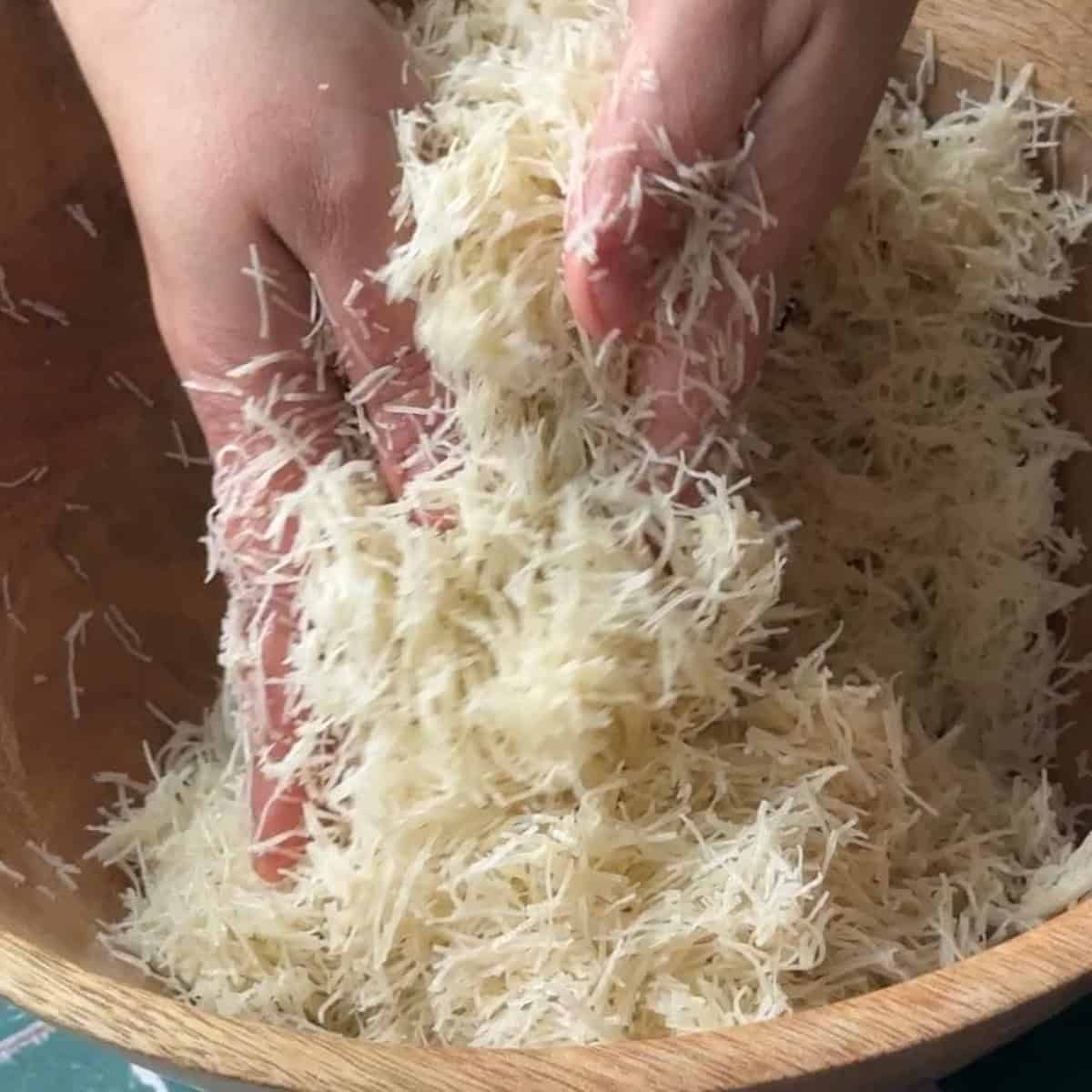 a woman mixing the shredded katayif dough with butter.
