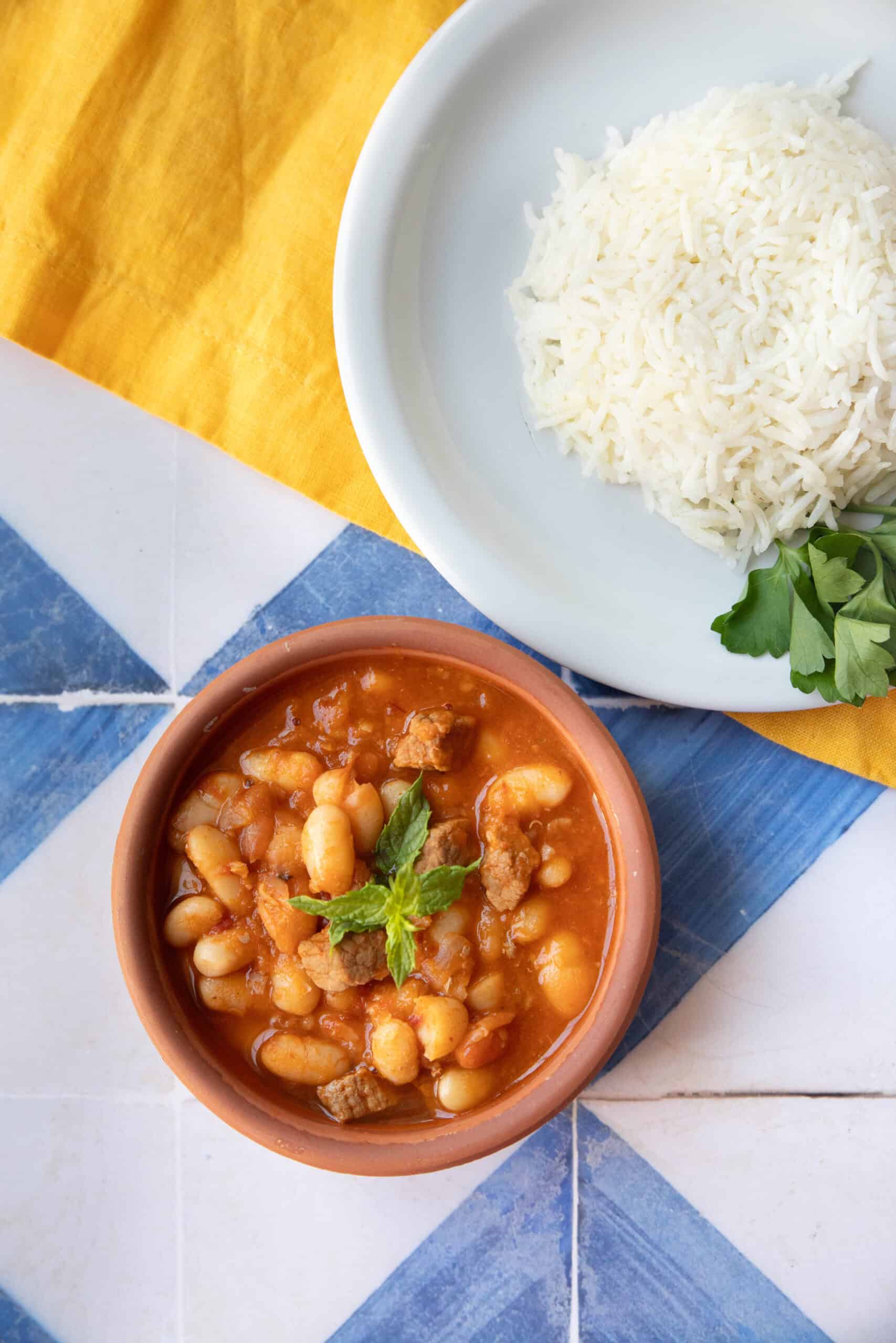 Easy Authentic Kuru Fasulye kuru fasulye served in brown bowl with white rice in a separate dish