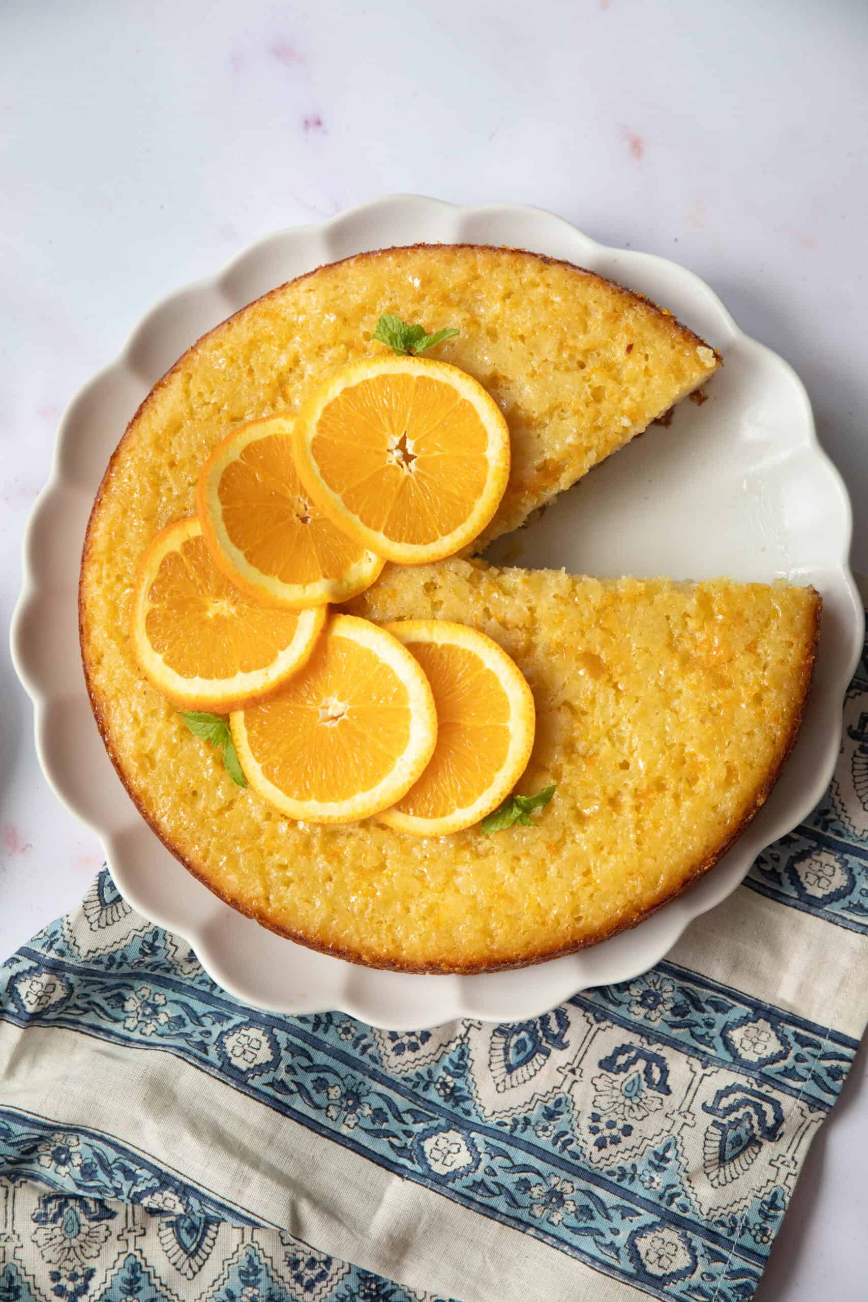 A golden-brown slice of Portokalopita Greek orange cake, topped with glistening orange syrup and served on a white plate
