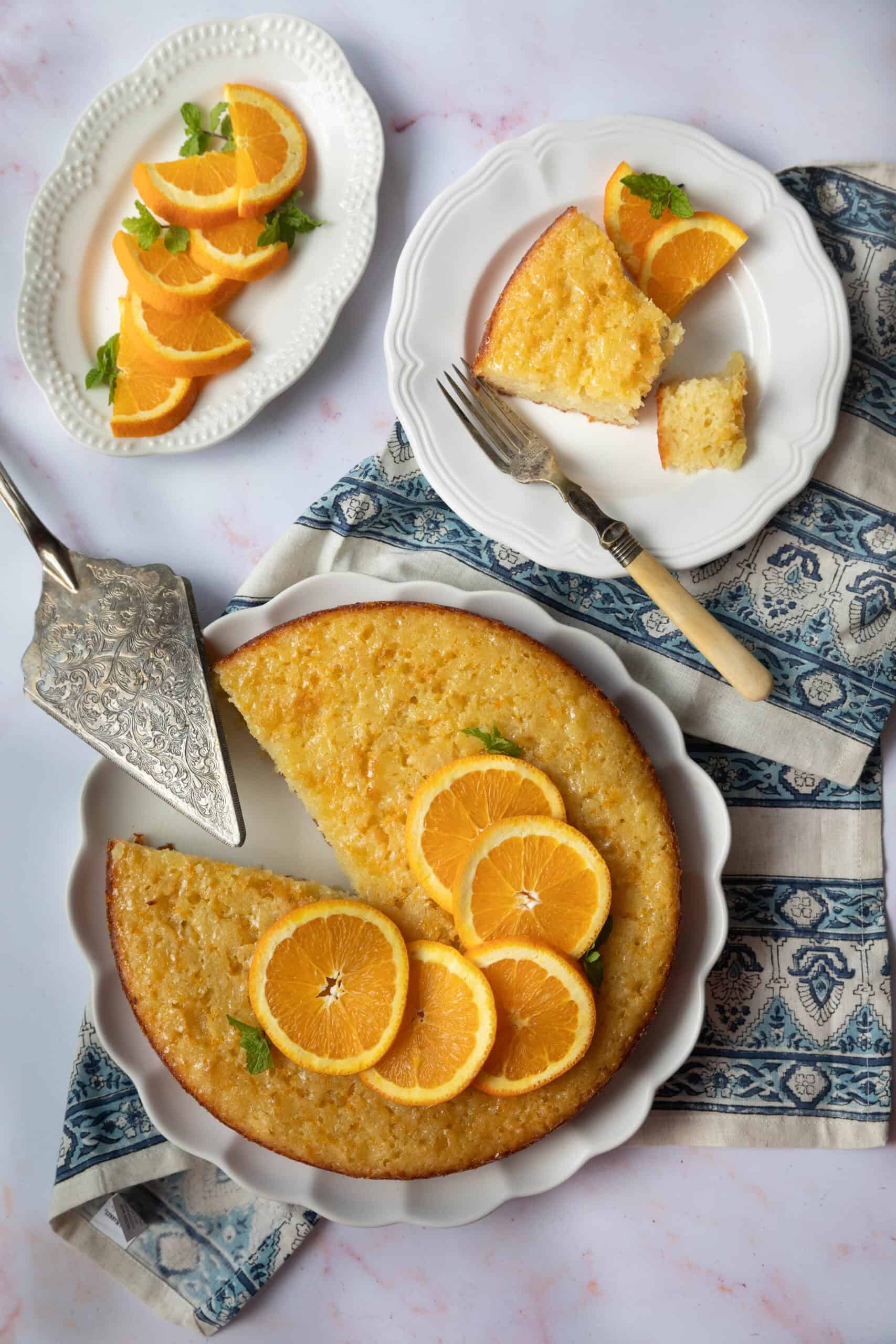 Greek Orange Cake A golden-brown slice of Portokalopita Greek orange cake, topped with glistening orange syrup and served on a white plate