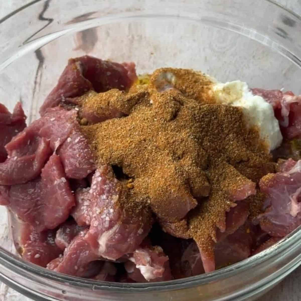Easy Authentic Homemade Lamb Shawarma add lamb meat to a bowl and add spices and other ingredients to marinate