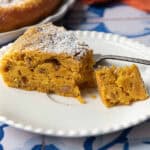 A beautifully baked pumpkin cake. The moist texture is visible, with hints of chopped walnuts and a warm, golden-brown crust