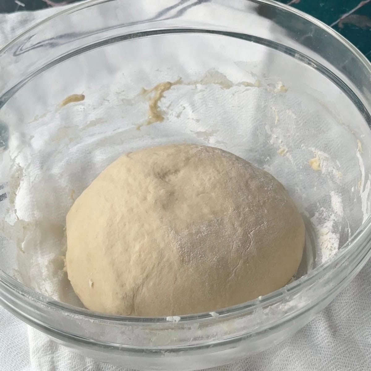 How To Make Pogaca Rolls A mixing bowl filled with a blend of flour, warm milk, warm water, instant yeast, sugar, and kosher salt mixed together.