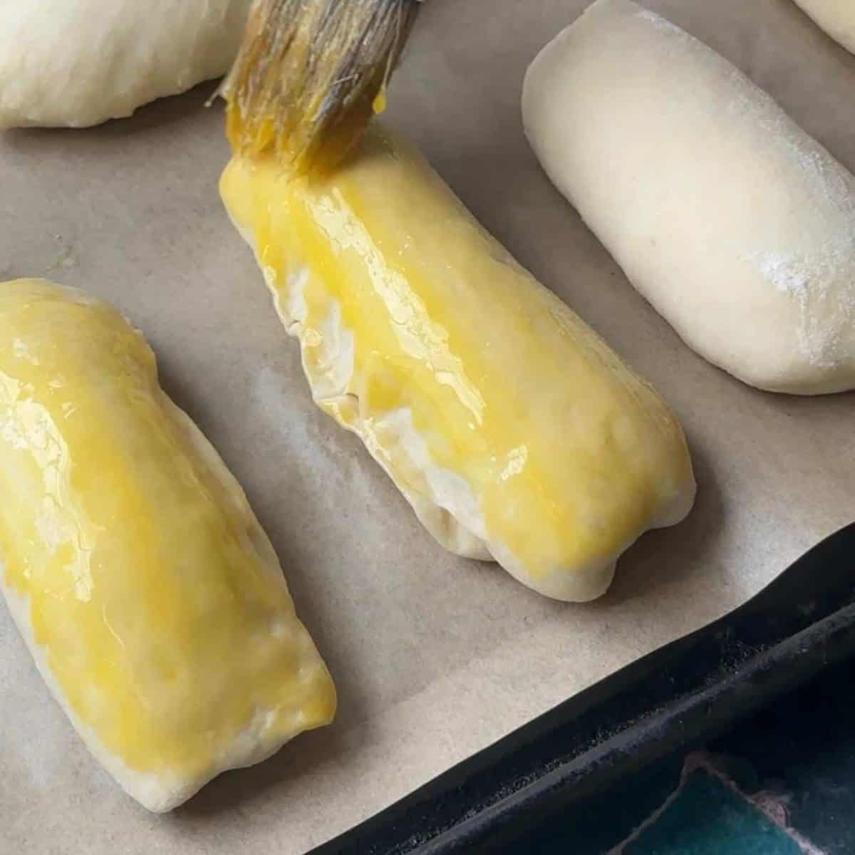 How To Make Pogaca Rolls Brushed Pogaca dough with a mixture of egg yolk and olive oil, giving them a shiny coating before baking in the oven.