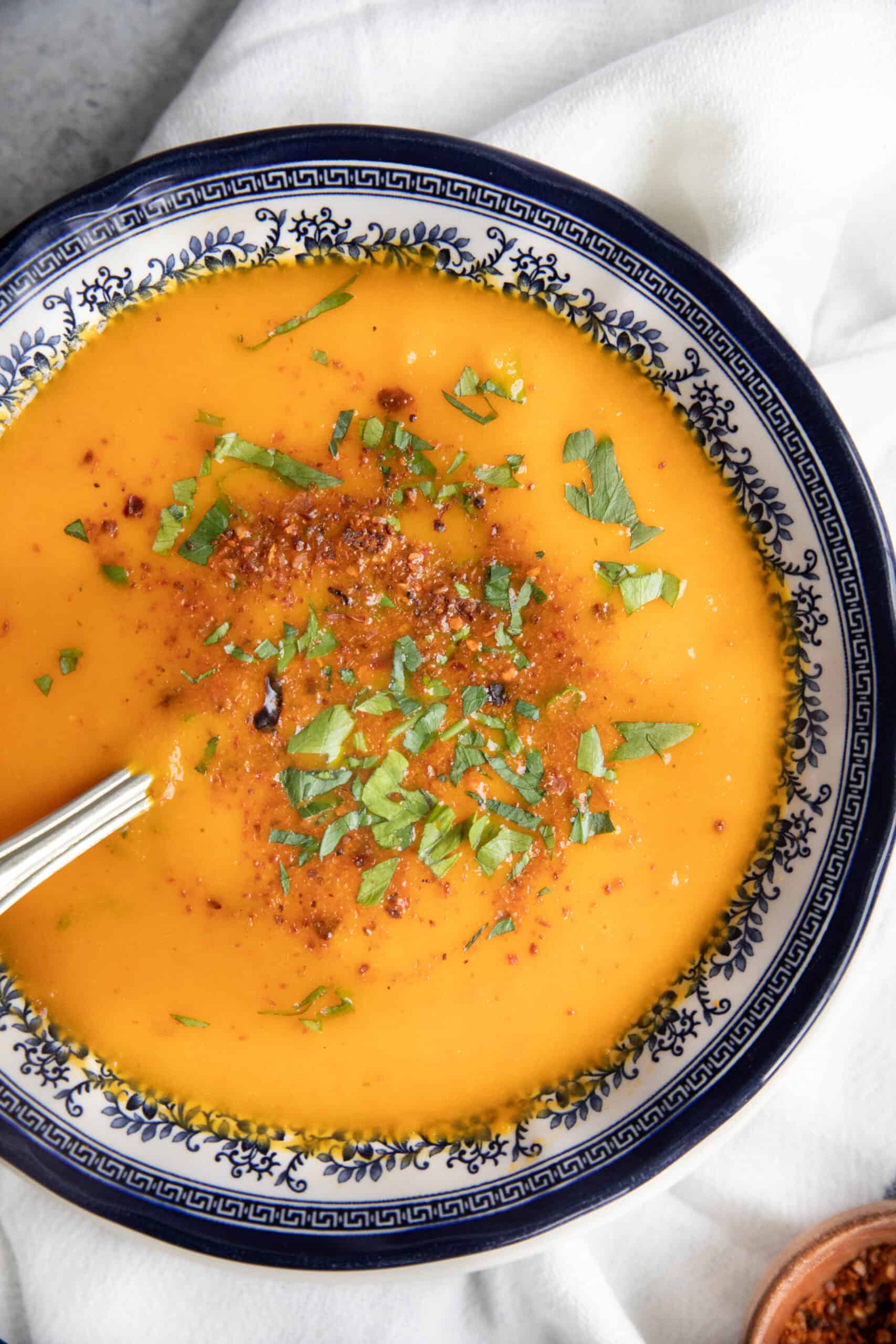 Easy Carrot Soup roasted carrot soup in decorative bowl garnished with parsley and dill