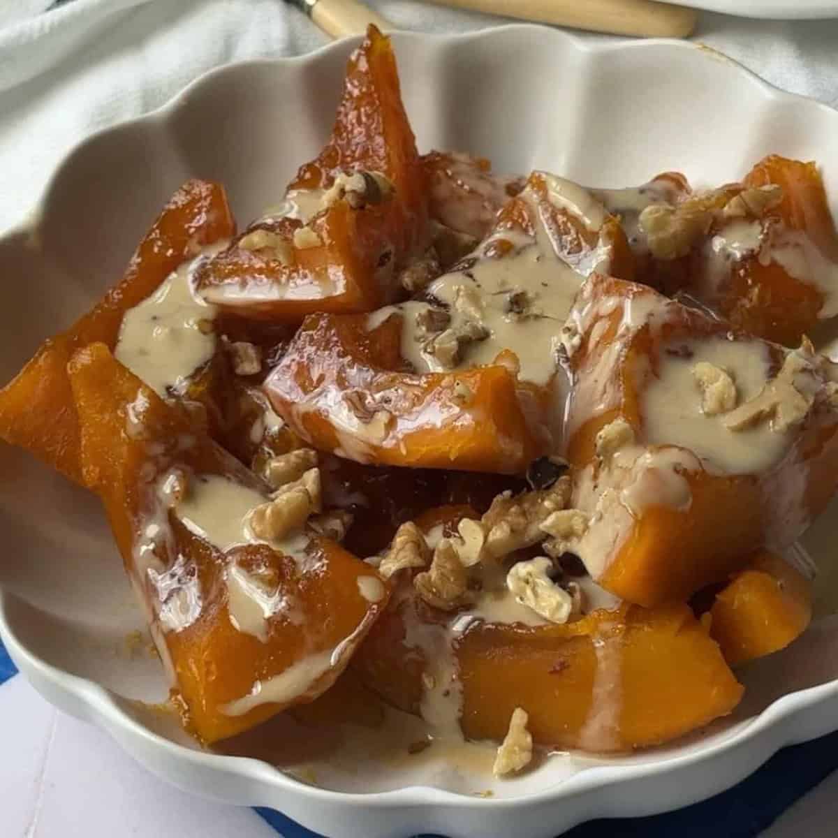 How to Make Kabak Tatlisi Dish of sweet pumpkin dessert drizzled with tahini and sprinkled with chopped walnuts.