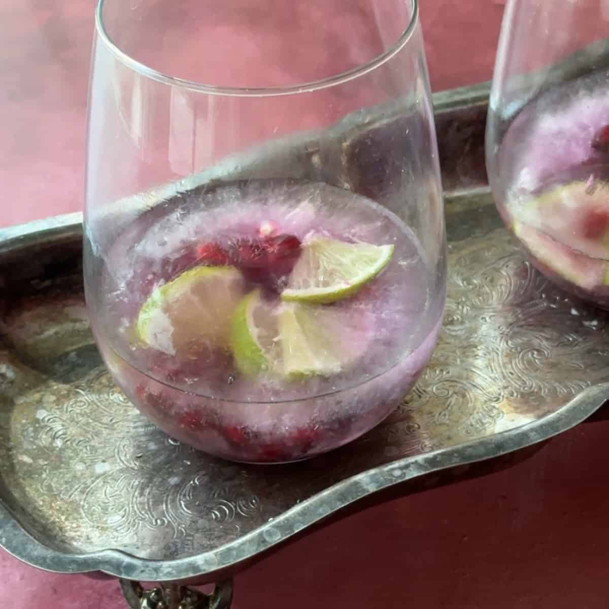 How to Make Pomegranate Mocktails frozen pomegranate arils and lime slices in glass