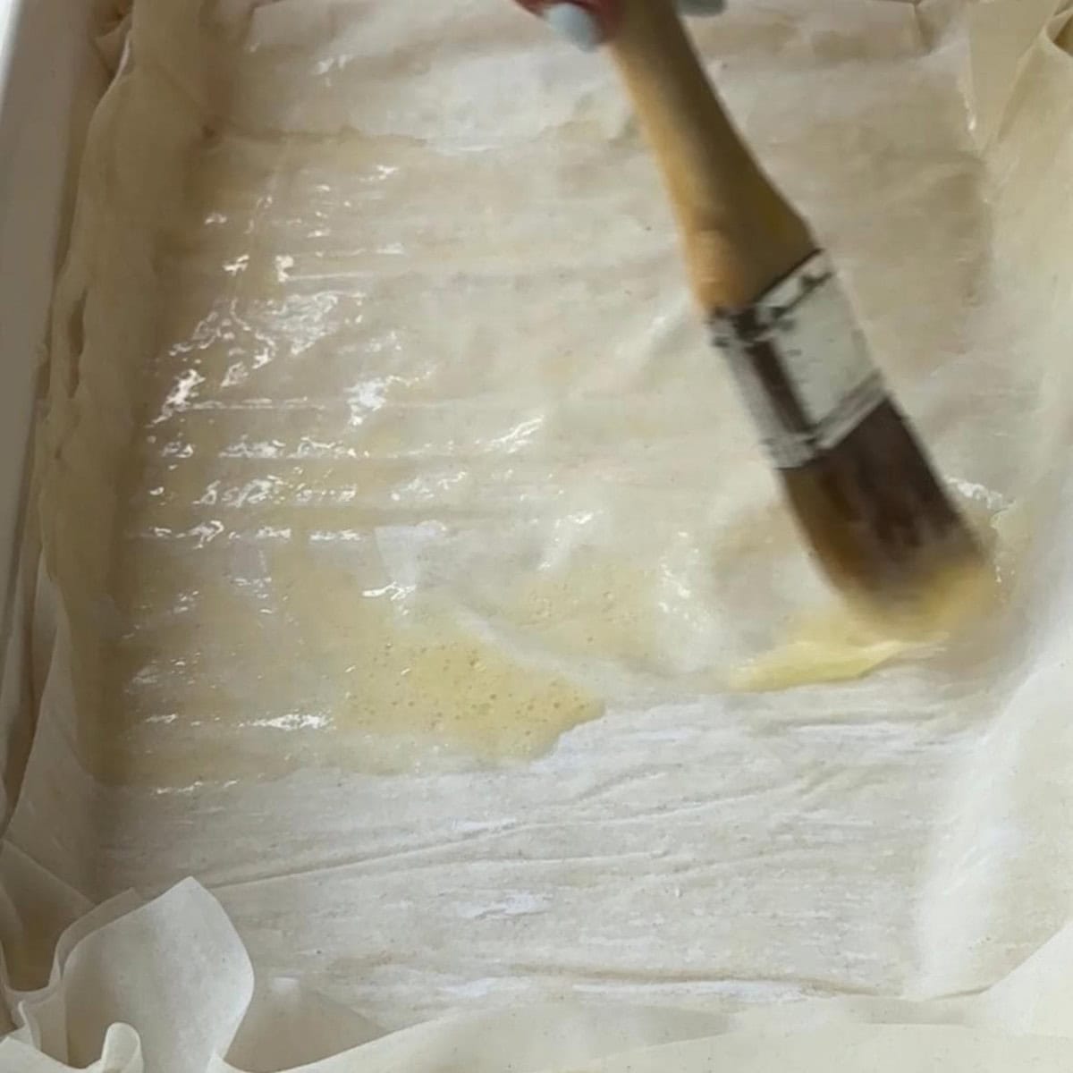 How to Make Spinach Feta Borek Phyllo dough sheets layered in a baking pan and brushed with sauce.