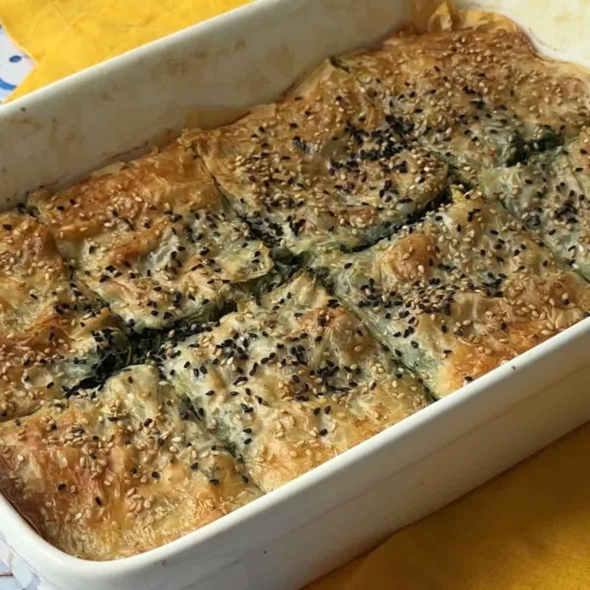 How to Make Spinach Feta Borek Golden-brown borek freshly baked, with a crispy top layer and sprinkled with sesame and nigella seeds.