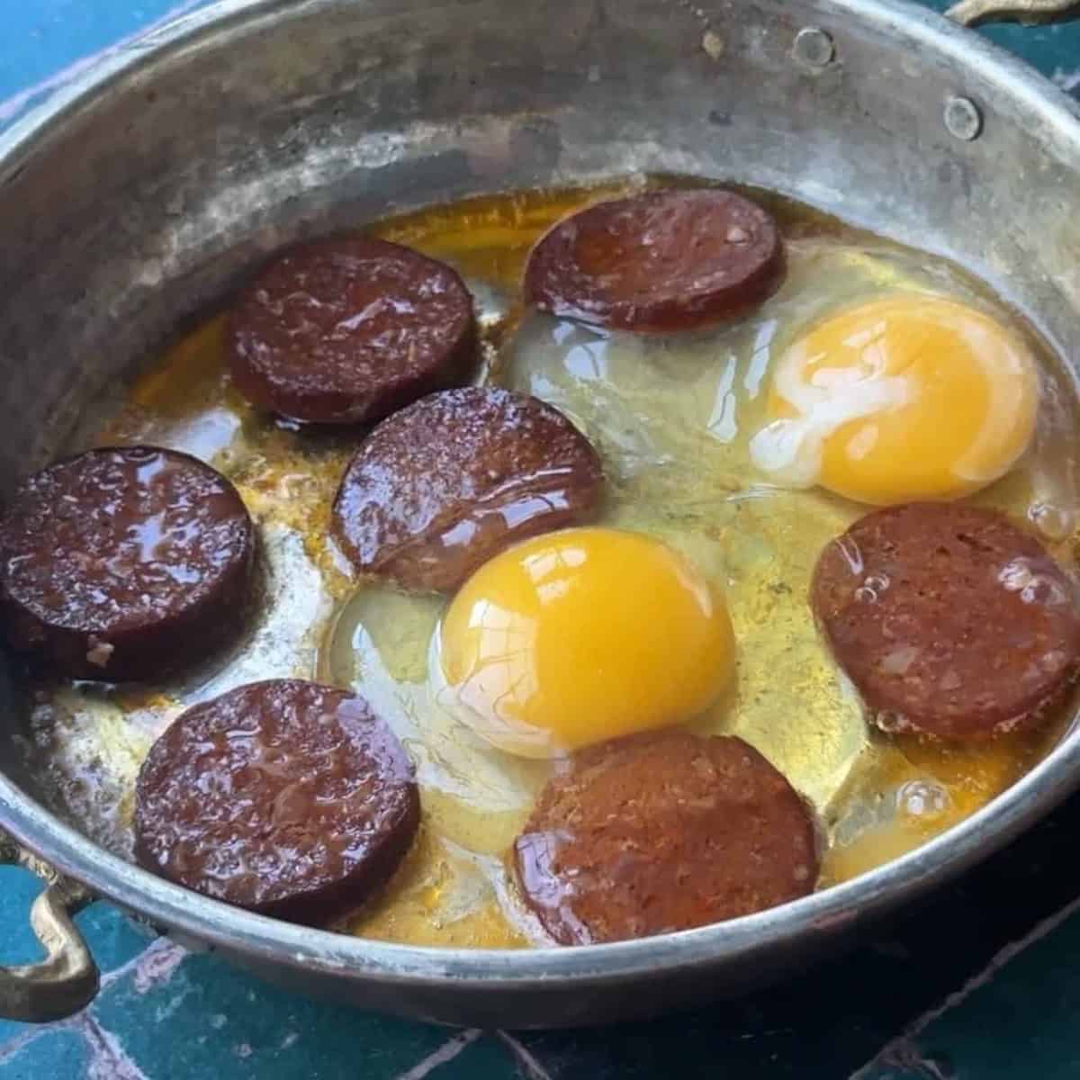 eggs cracked over the sucuk in pan