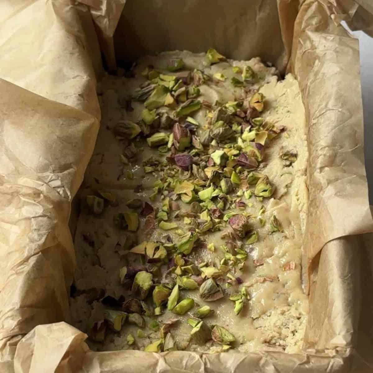 how to make tahini halva spread the mixture and sprinkle more pistachios on top and lightly press them down with the excess parchment