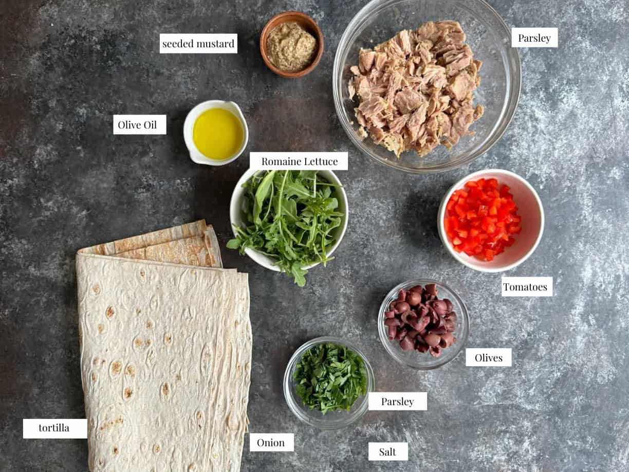 the ingredients needed to make Mediterranean tuna wrap: tuna, olive oil, diced red pepper, seeded mustard, chopped kalamata olives, arugula, chopped parsley, and wraps