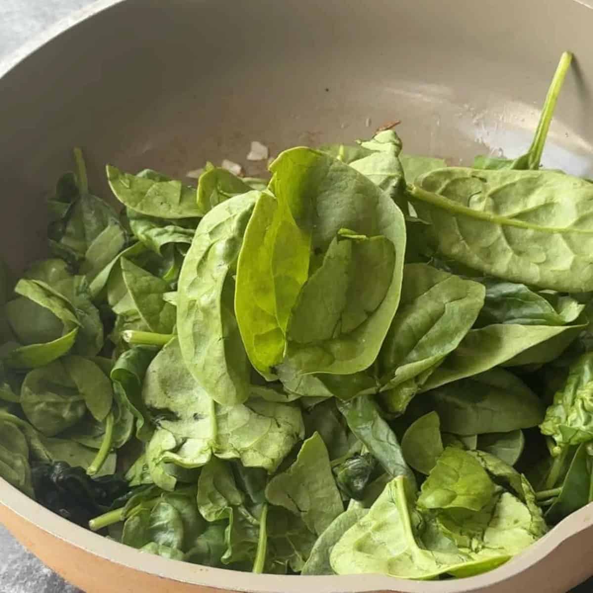 Spinach Filling for Turkish Pide baby spinach leaves in a pan with sauteed chopped onion