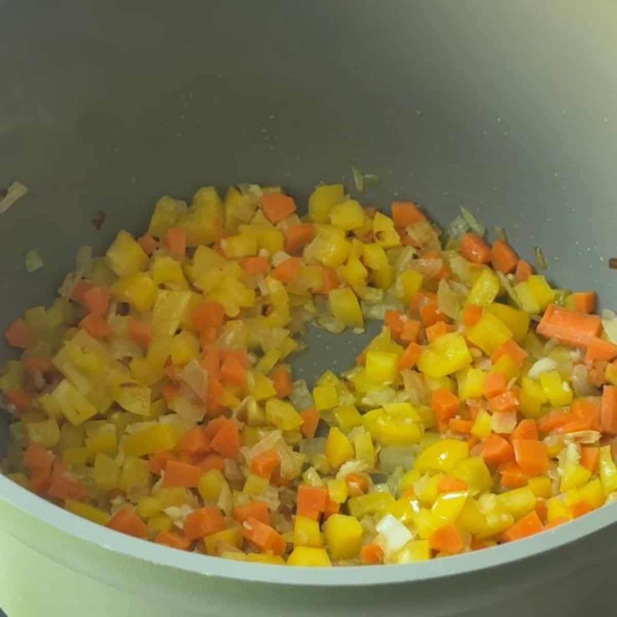 Chopped carrot and bell pepper added to the pot with sautéed onion and garlic.