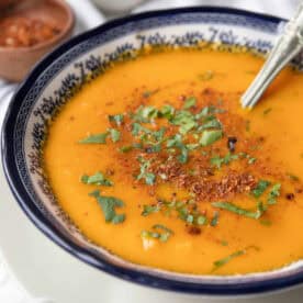 roasted carrot soup in decorative bowl garnished with parsley and dill