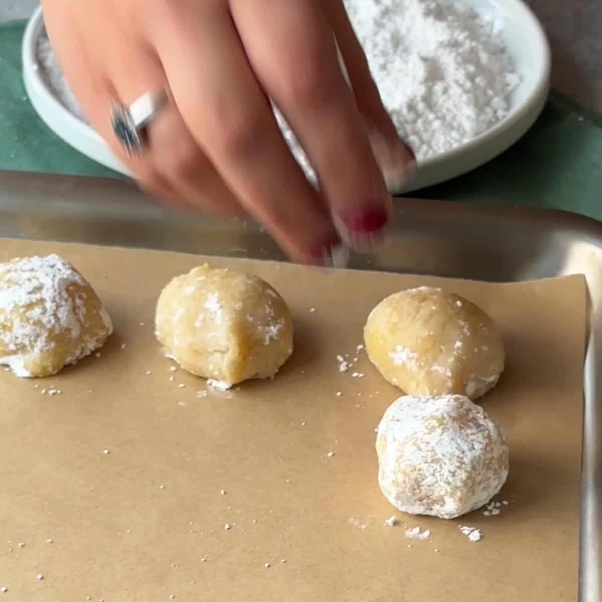 How to Make Amaretti Cookies sprinkle powdered sugar on amaretti dough balls