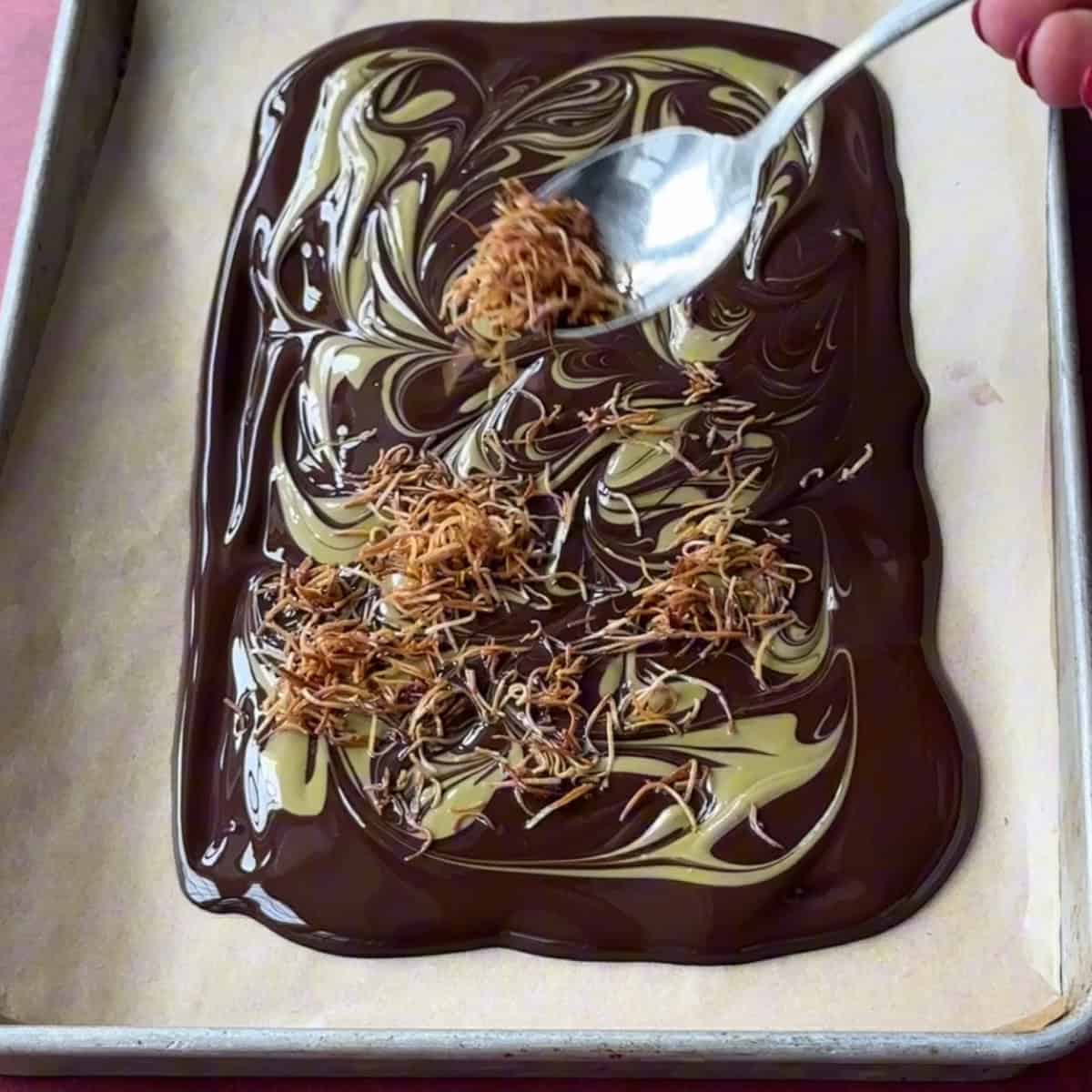 Adding cooked kataifi to melted dark chocolate with pistachio cream.