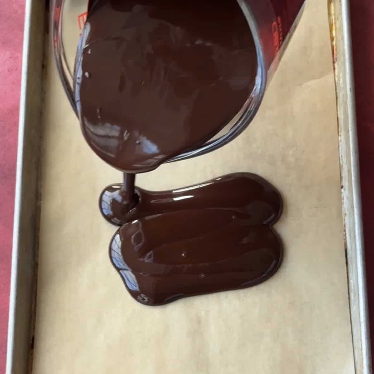 pouring the dark chocolate on a parchment paper.