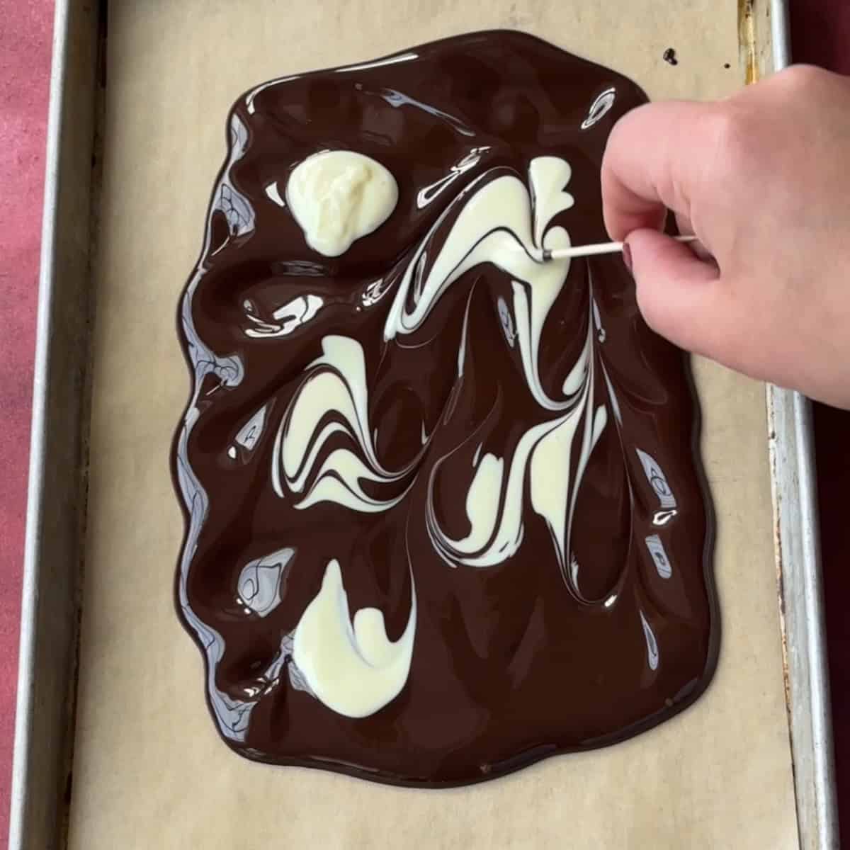 Swirling melted white chocolate with melted dark chocolate.