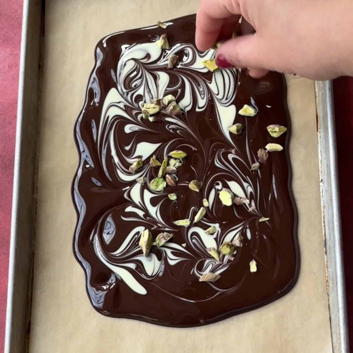 Topping melted white and dark chocolate with chopped pistachios.