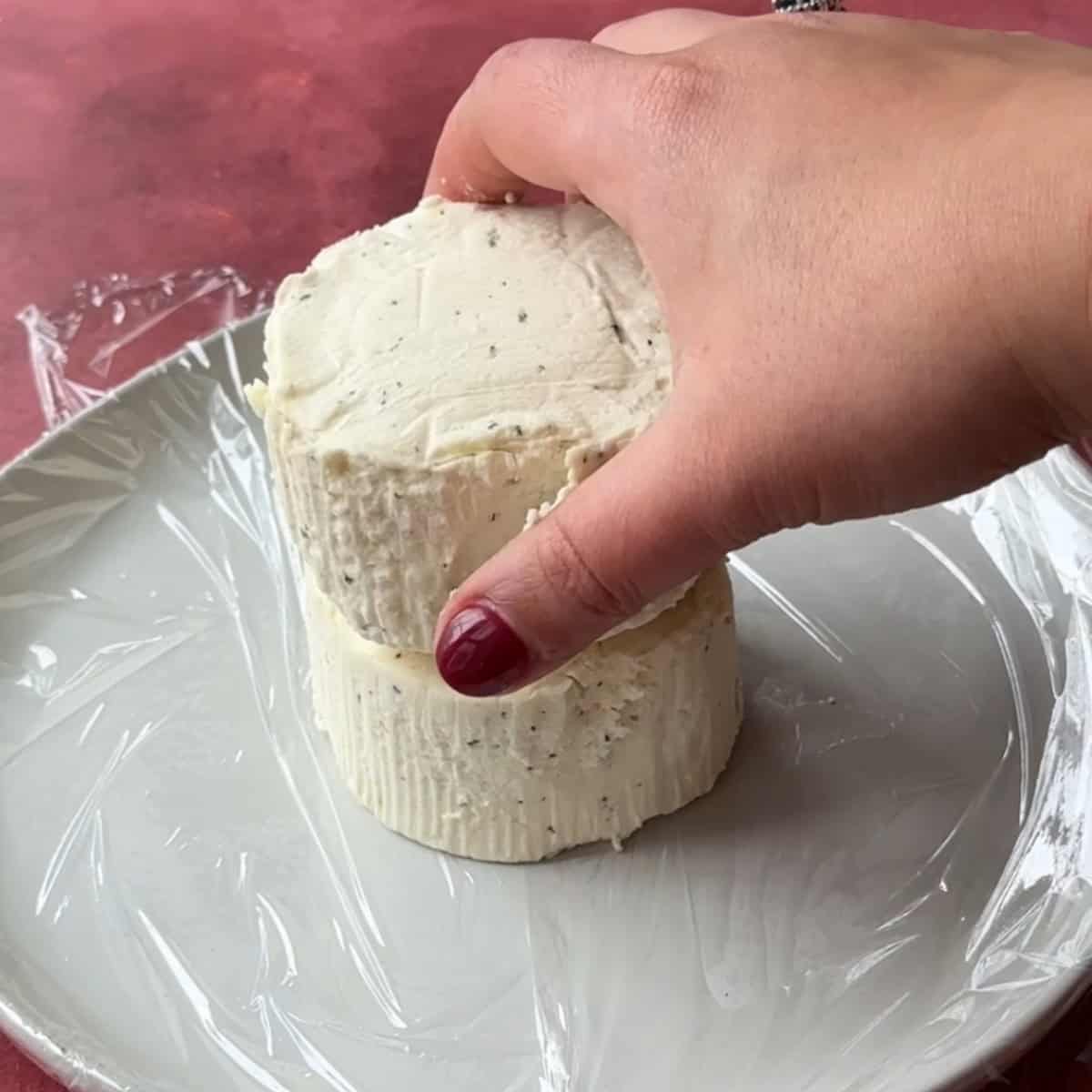 How to Make Christmas Cheese Ball put 2 Boursin cheese on plastic wrap in serving platter
