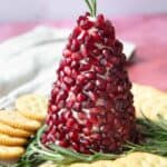 Christmas tree cheese ball served on a plate with sprigs of rosemary and crackers around it
