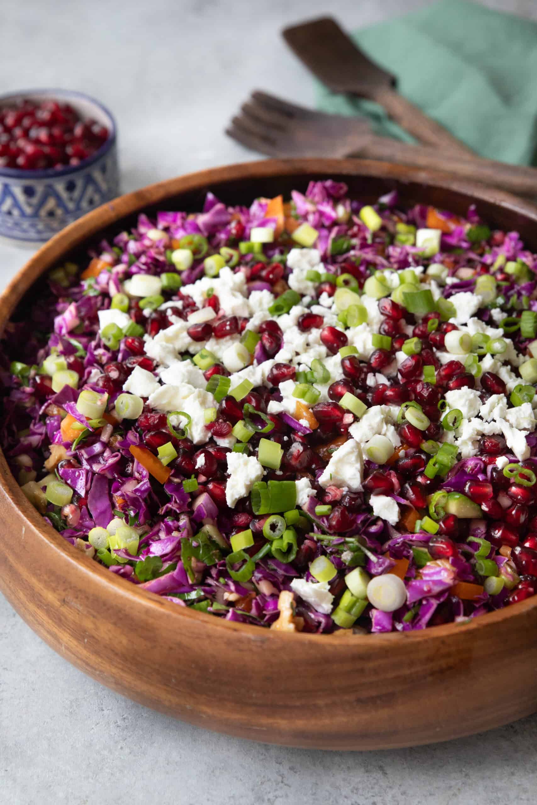 Easy Red Cabbage Pomegranate Salad red cabbage pomegranate salad served in a wooden bowl with a small bowl of pomegranate arils in the background