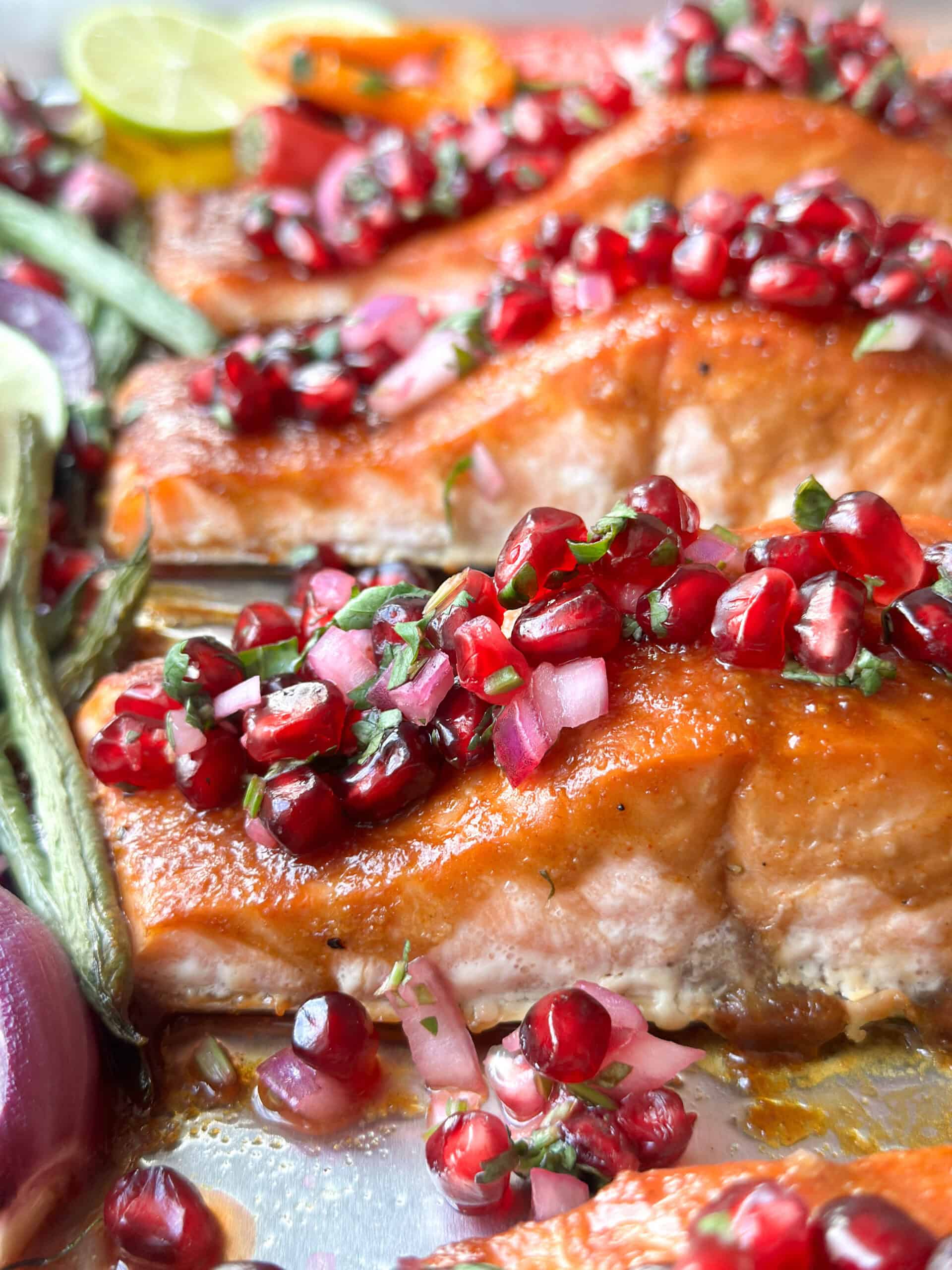 sheet pan salmon topped with pomegranate salsa and surrounded by veggies