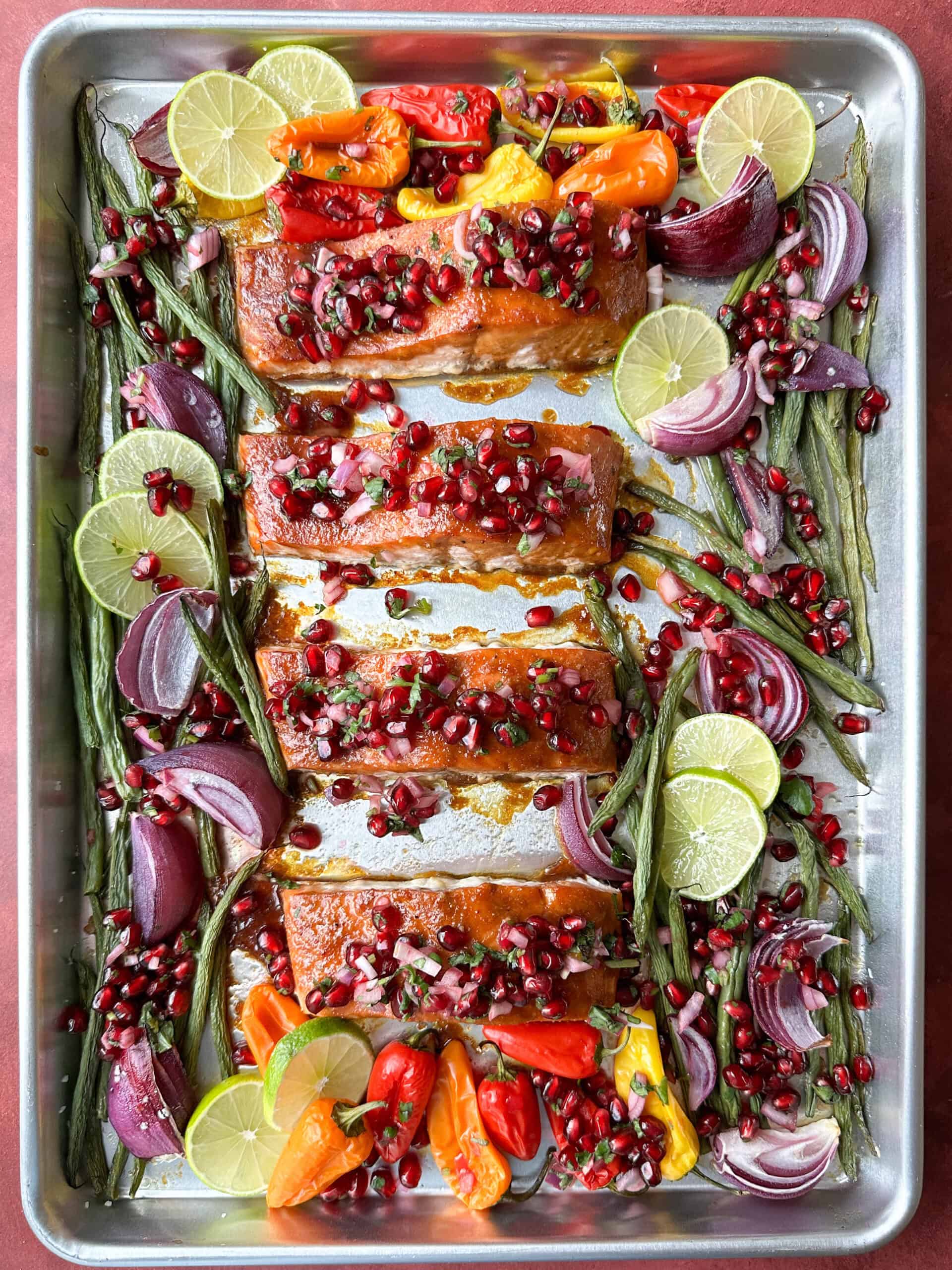 sheet pan salmon topped with pomegranate salsa and surrounded by veggies