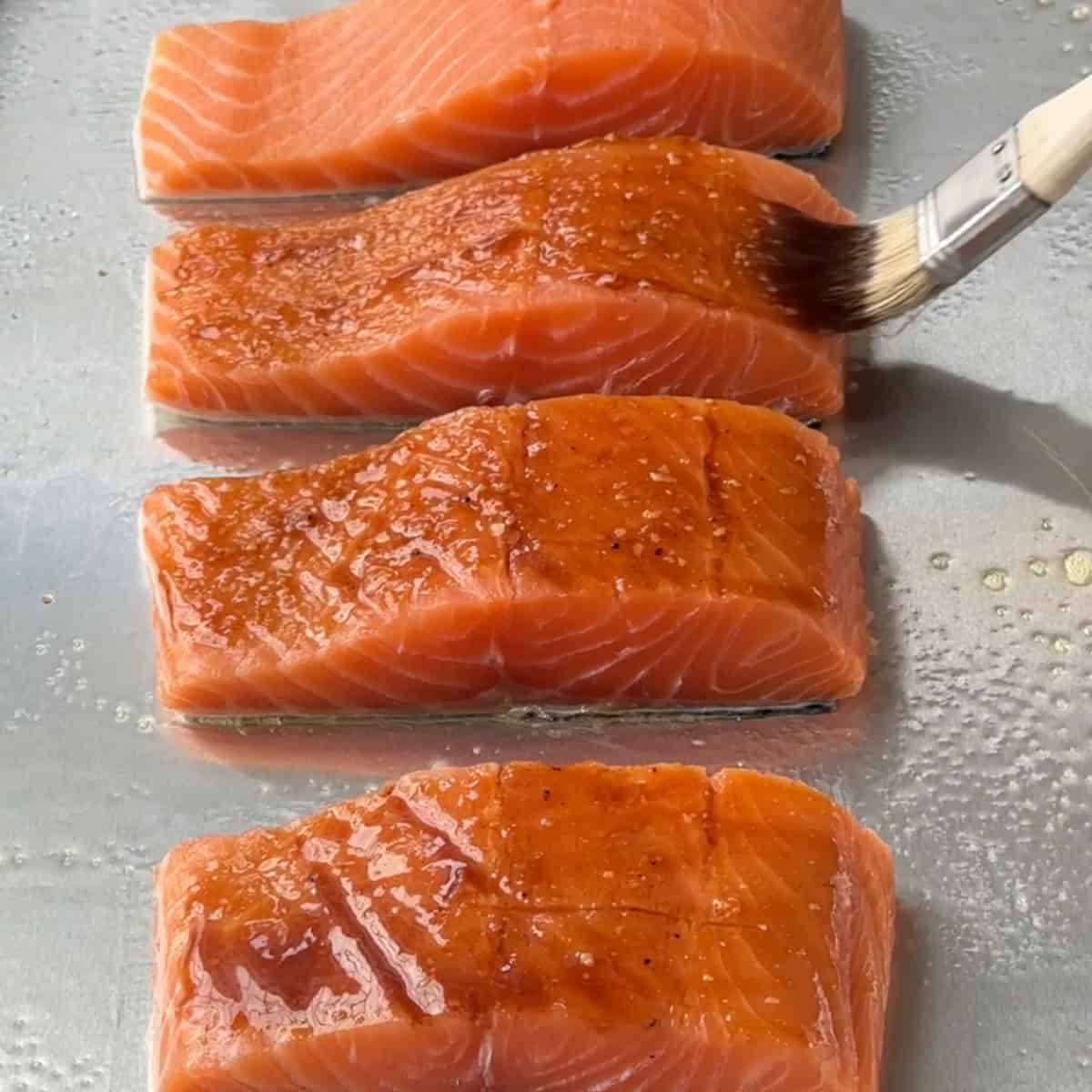 salmon getting brushed with marinade in the sheet pan