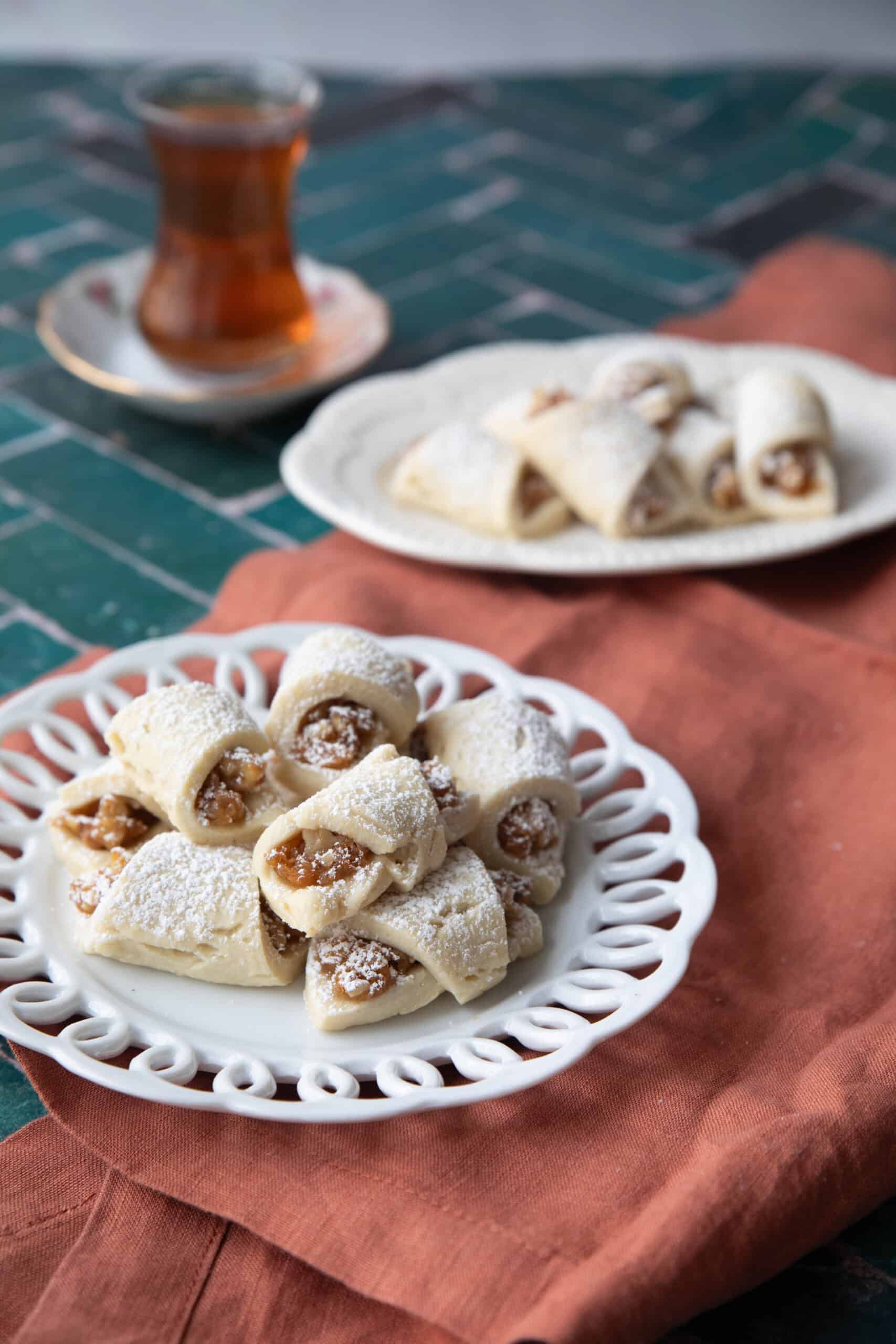 Turkish Apple Cookies (Elmali Kurabiye) Turkish apple cookies or elmali kurabiye, stacked on two decorative white plates served with tea