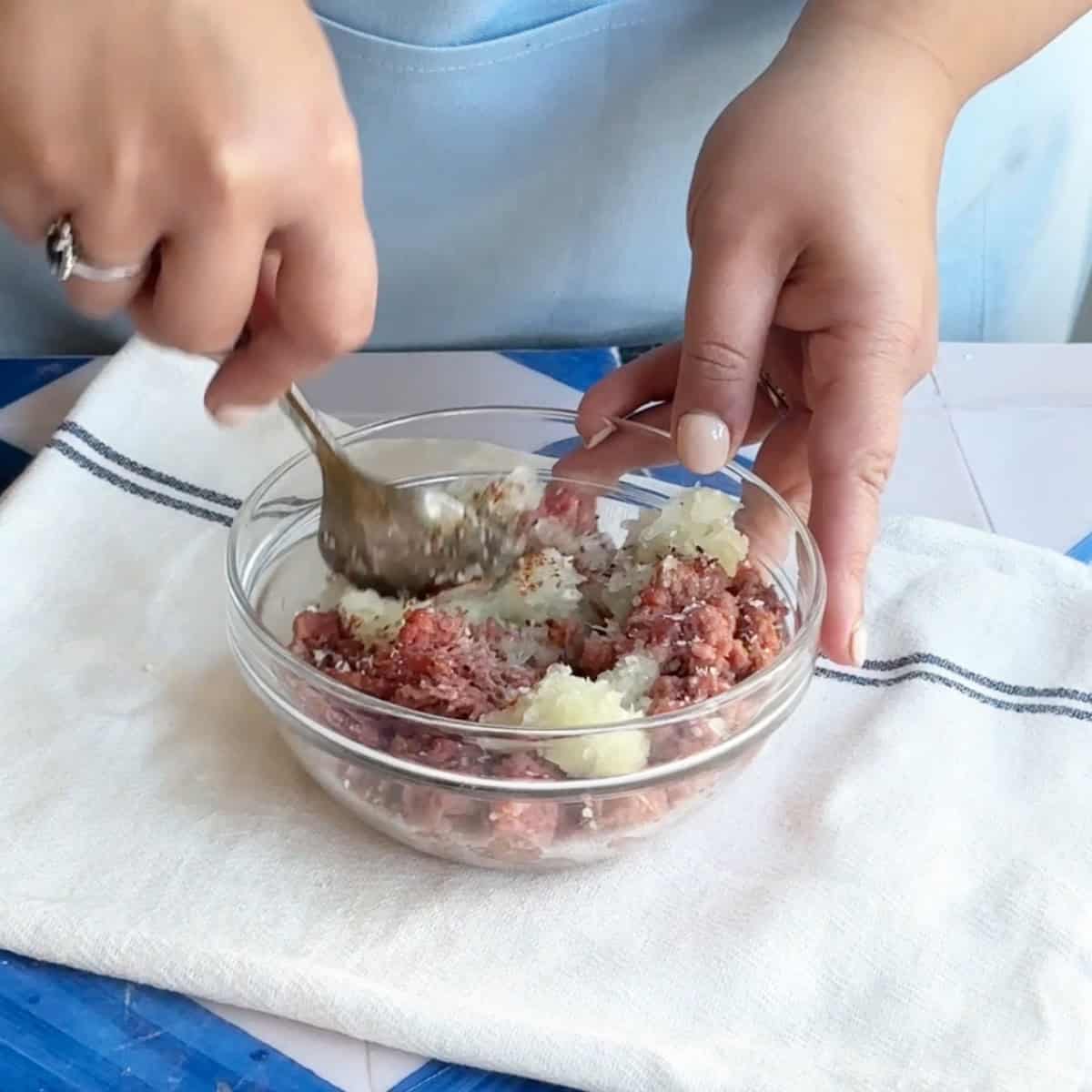 How to Make Manti Beef Filling mixing the beef and onion mixture using a spoon