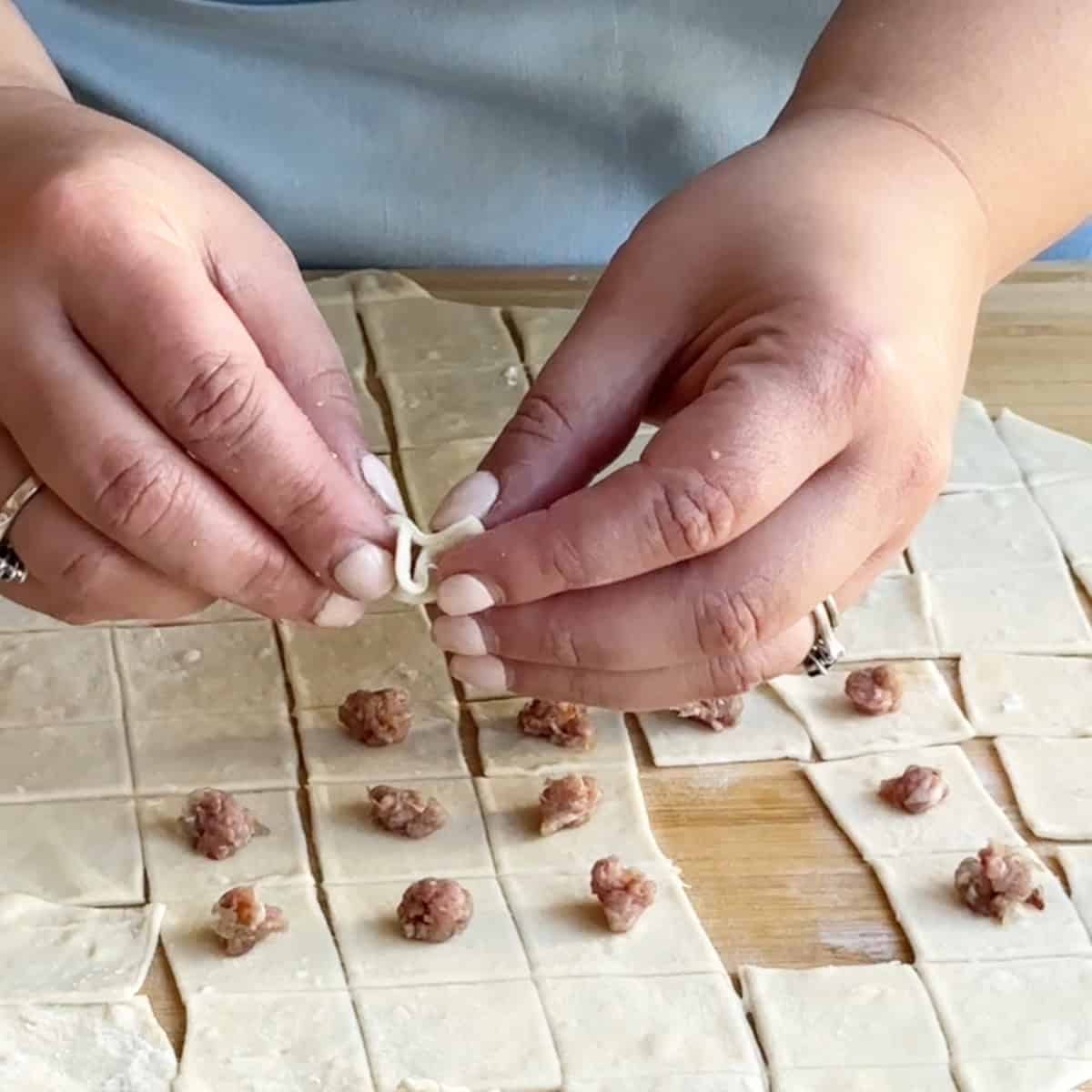 How to Shape Manti Hands carefully pinching opposite corners of each square together to form tiny, well-sealed dumplings
