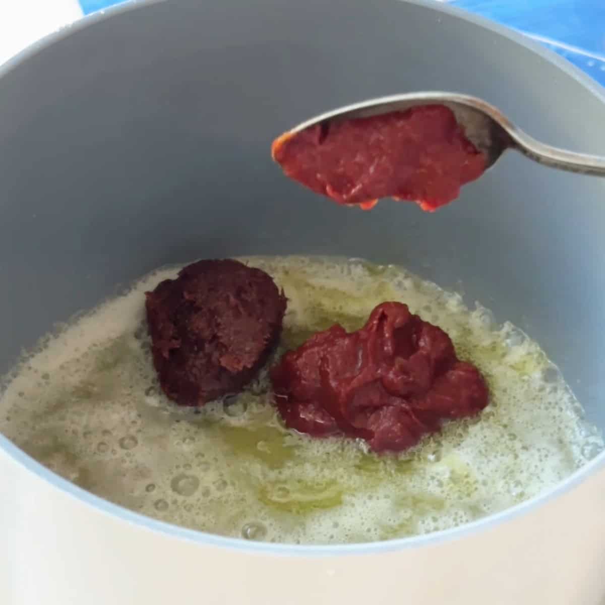 How to Make Manti Sauce Pepper paste and tomato paste being stirred into the melted butter and olive oil