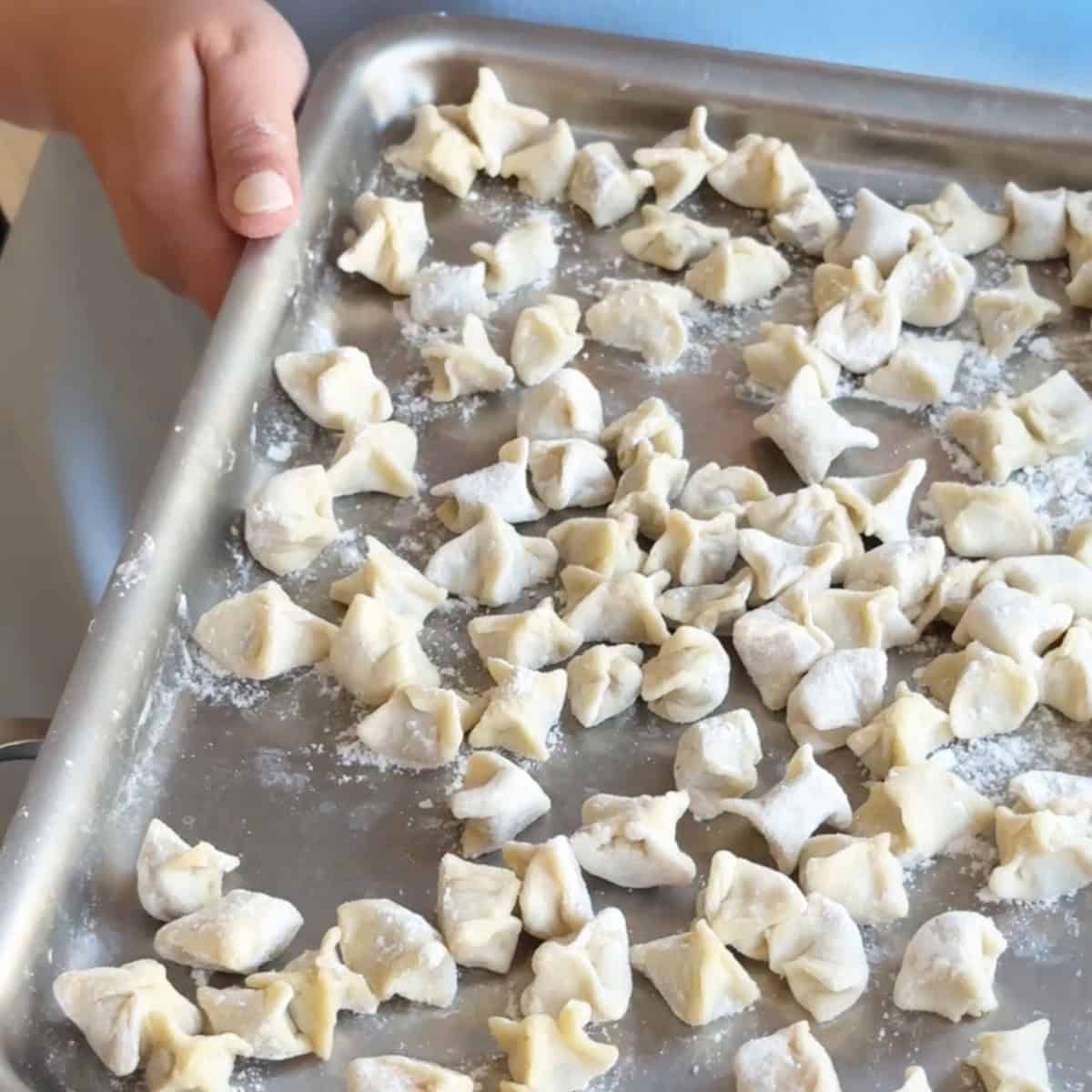 Shaping Manti Dough A tray of neatly shaped manti dumplings lined up, ready for cooking.
