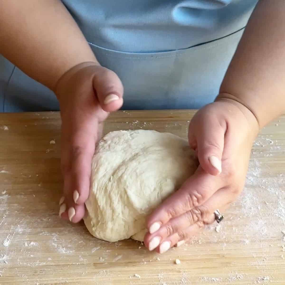 Best Manti Dough Recipe Hands kneading the dough on a floured surface until smooth and elastic