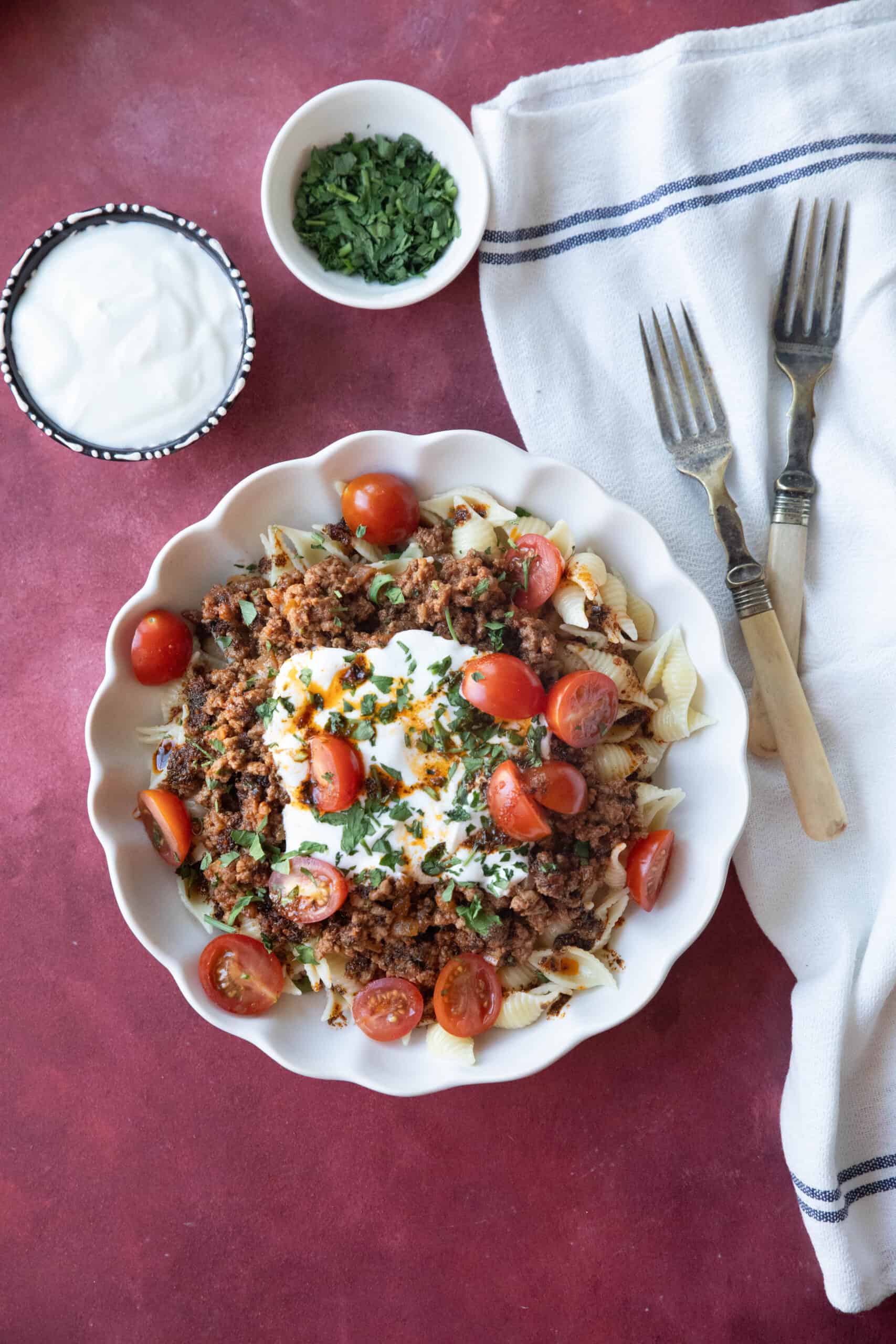 Fake Turkish Manti A serving of Turkish pasta in a white bowl with layers of beef, yogurt sauce, and spiced butter.