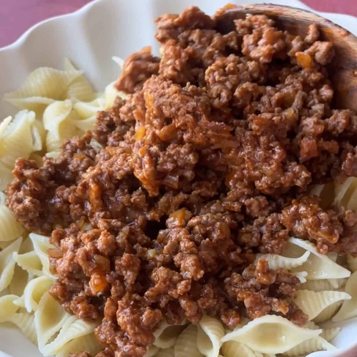 Turkish Ground Beef Pasta A plate of cooked pasta being topped with the rich ground beef sauce.
