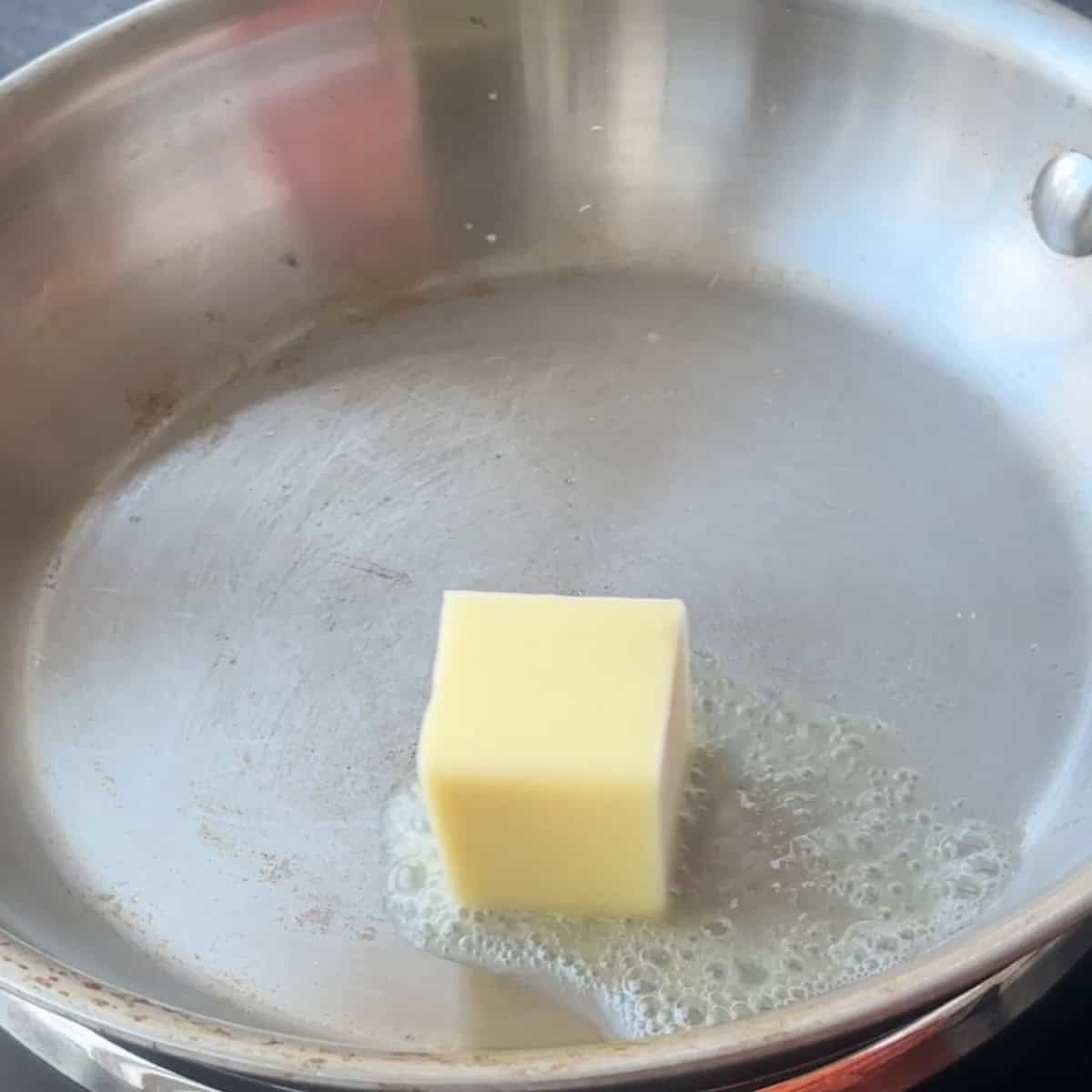 a cube of butter melting in a sauce pan