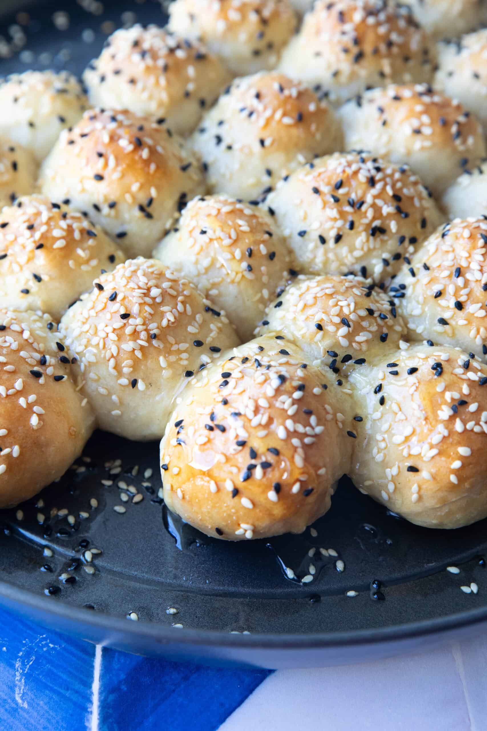 A close-up of honeycomb bread buns, showcasing their soft, fluffy texture and glossy honey coating, arranged in a beehive pattern.