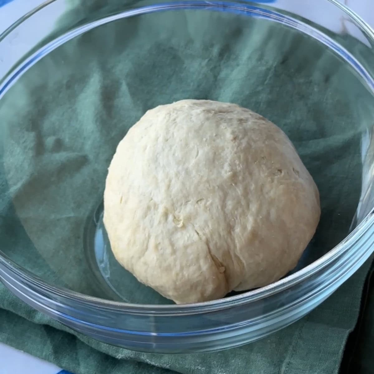 a round dough placed in a glass bowl